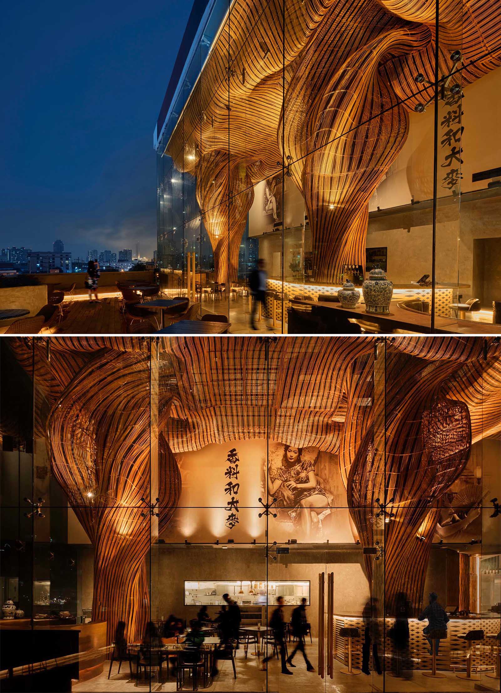 A modern restaurant with a glass facade that showcases flowing rattan sculptures inside.