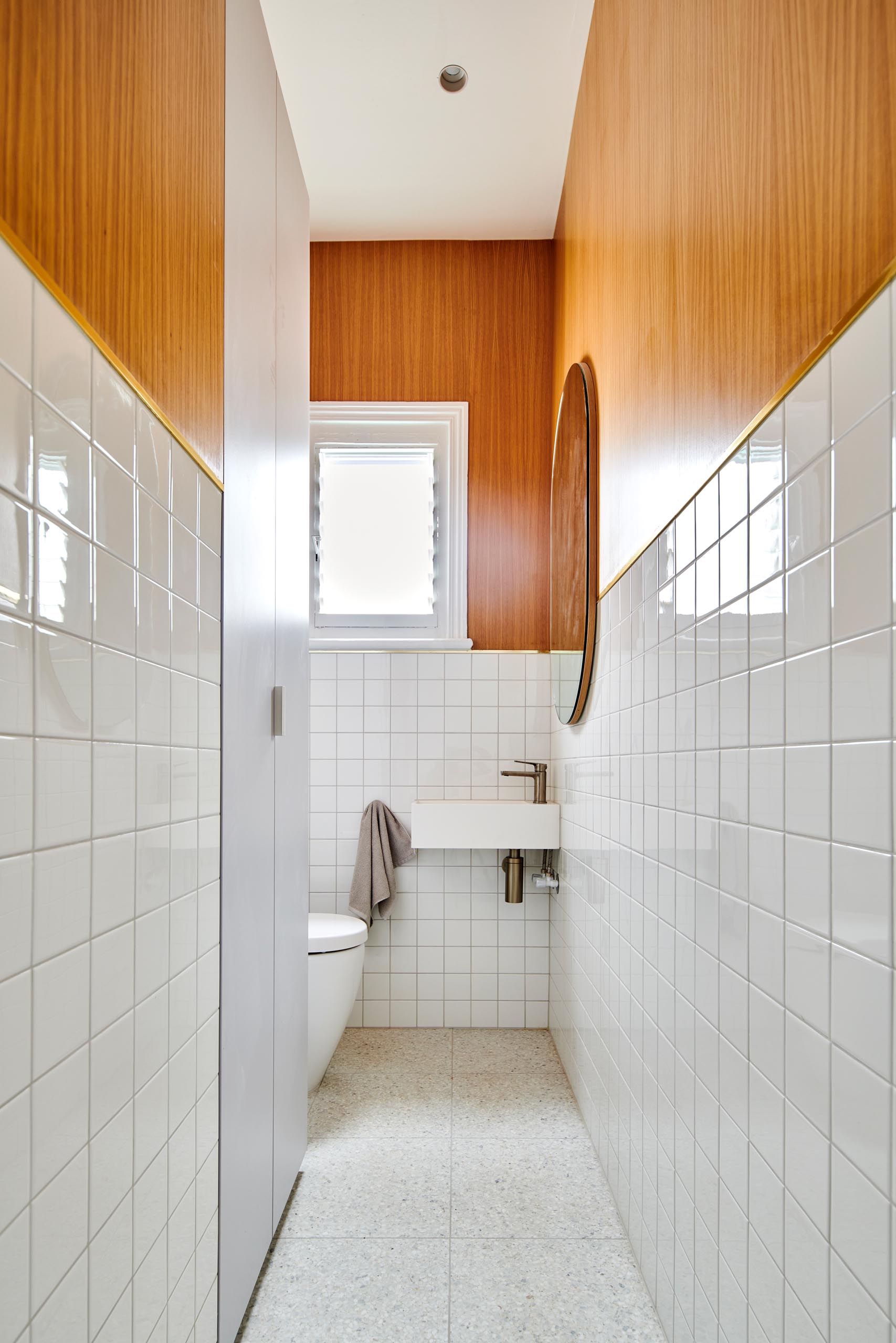 A modern white bathroom with wood accent.