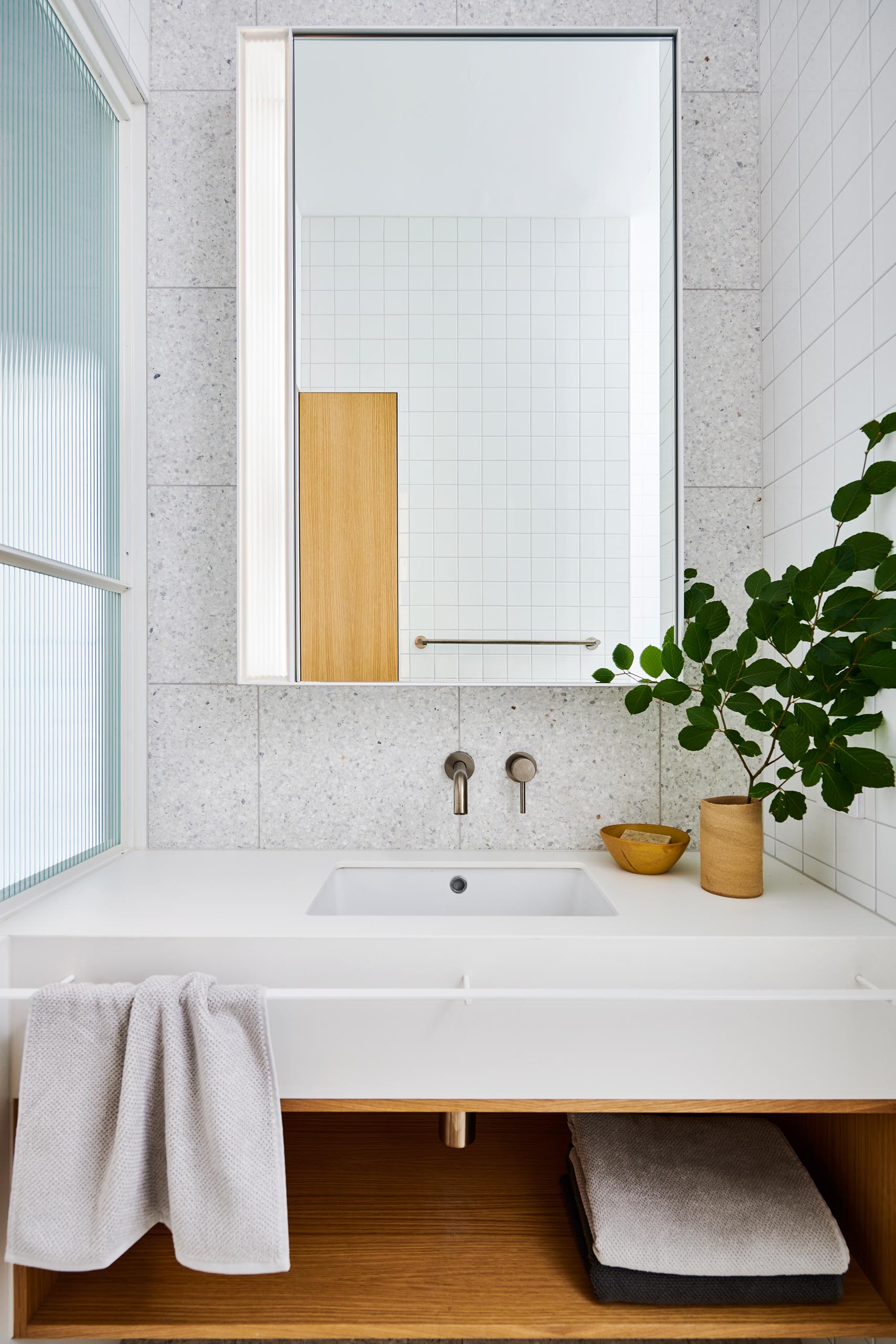 A modern white bathroom with wood accent.