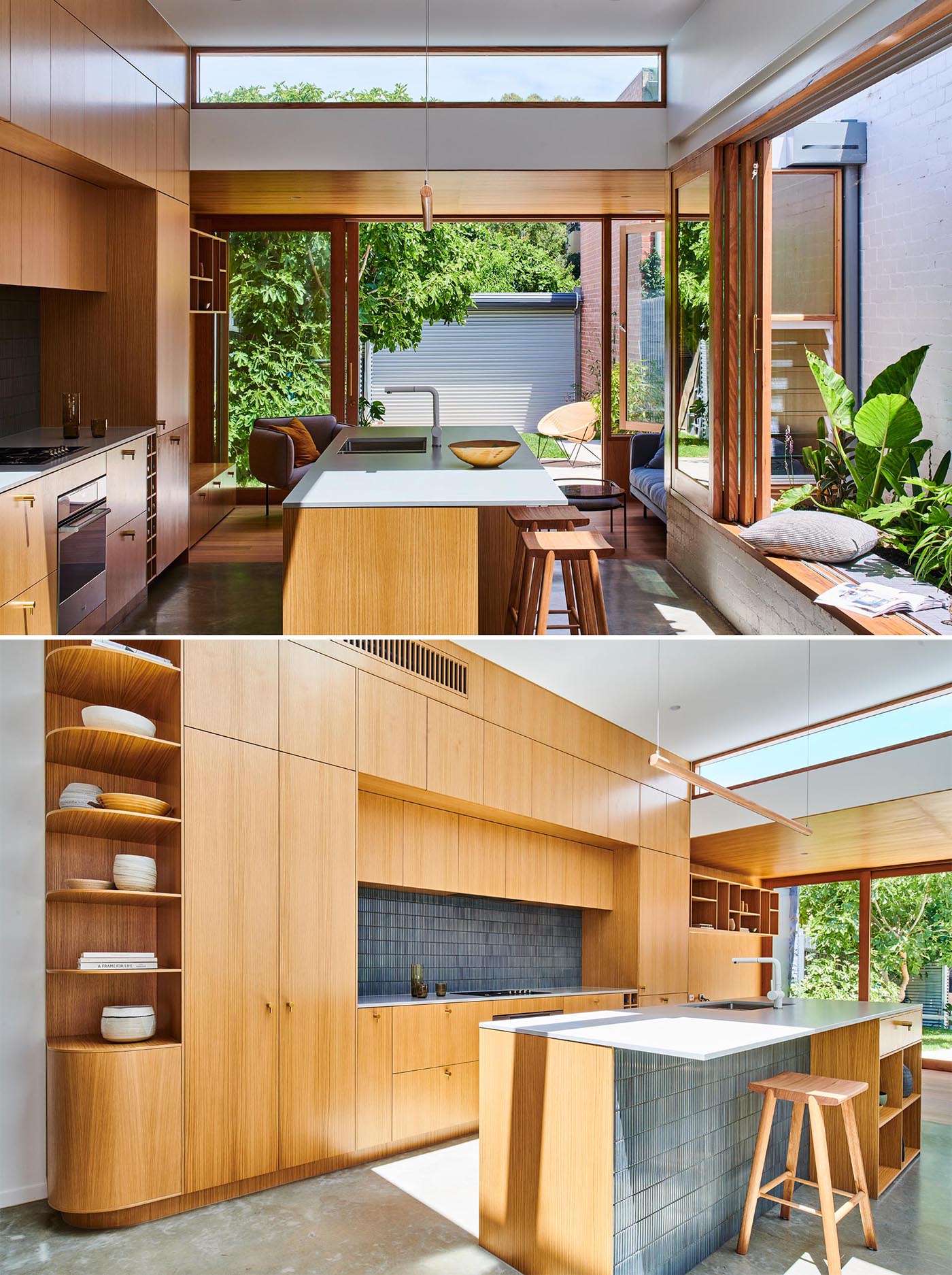 A modern wood kitchen with a large window open to a small garden, gray tiles, an island, open shelving, white countertop, and built-in wine storage.