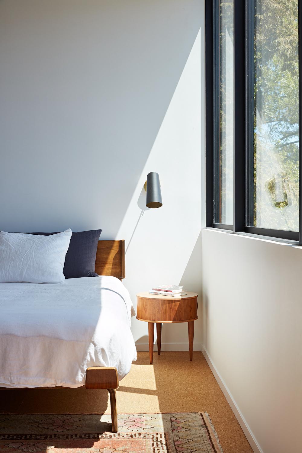 This remodeled primary bedroom has black accents, an en-suite bathroom, a small sitting area, and a desk tucked away into an alcove.