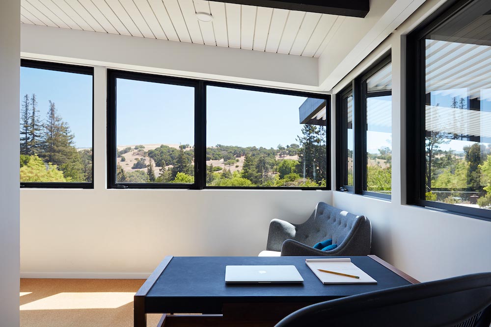 This remodeled primary bedroom has black accents, an en-suite bathroom, a small sitting area, and a desk tucked away into an alcove.