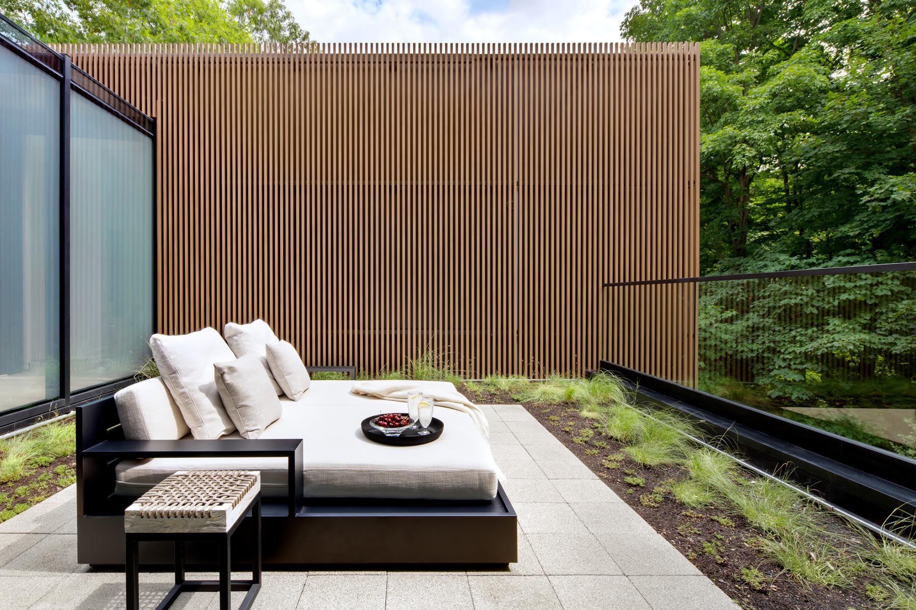 This modern primary bedroom has floor-to-ceiling windows, and a sliding glass opens to a private outdoor space.