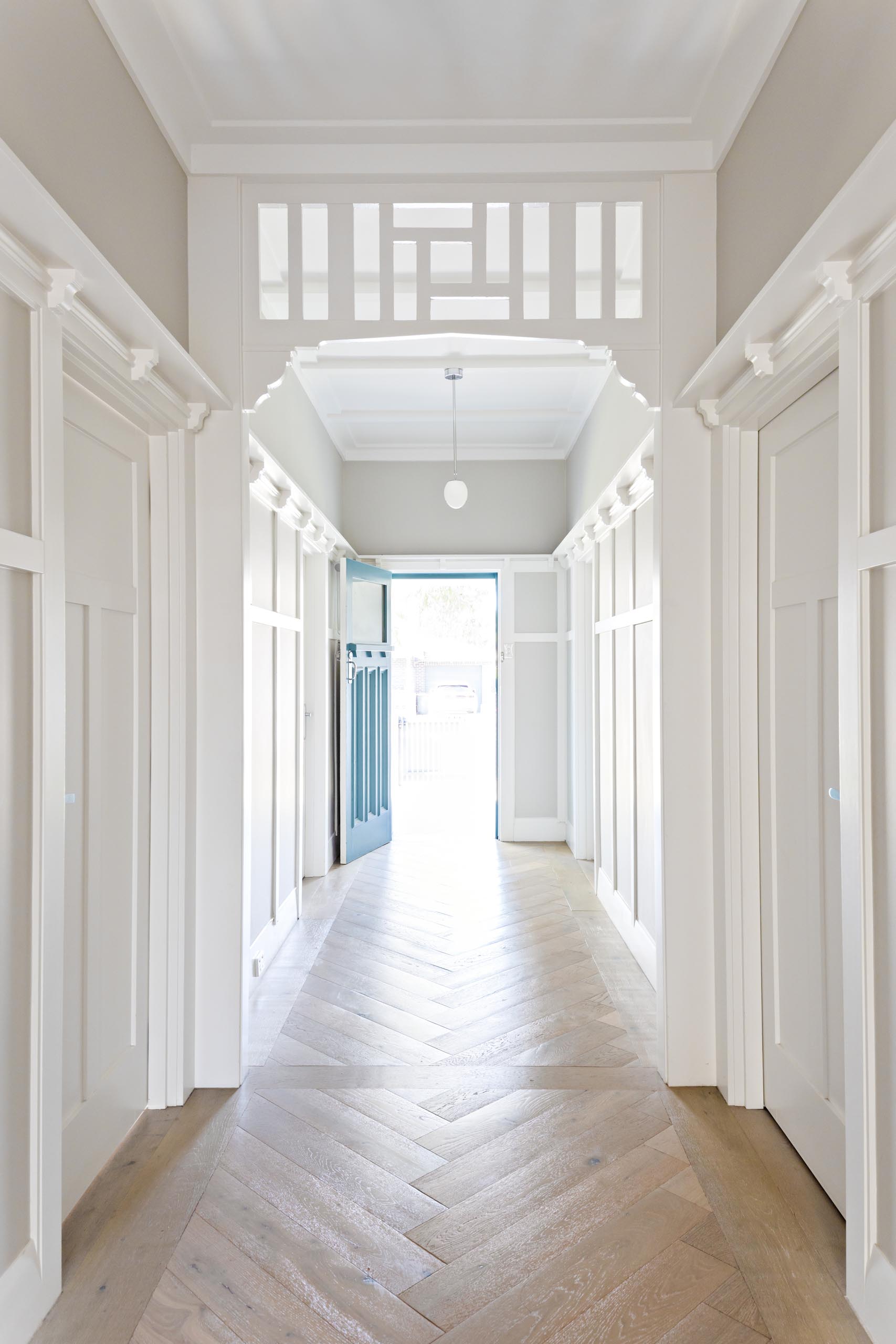 A renovated hallway with herringbone wood flooring.