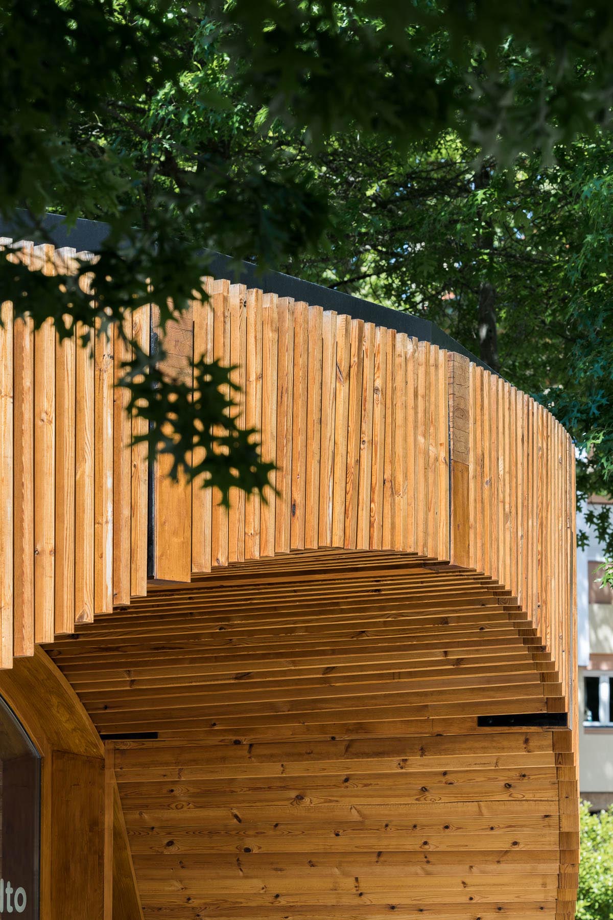 A small modern building has a circular design that's covered in vertical wood slats.