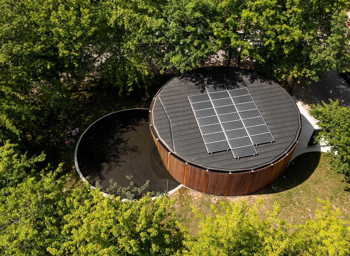The circular design of this modern building is accented by a curved water feature as well as solar panels on the roof.