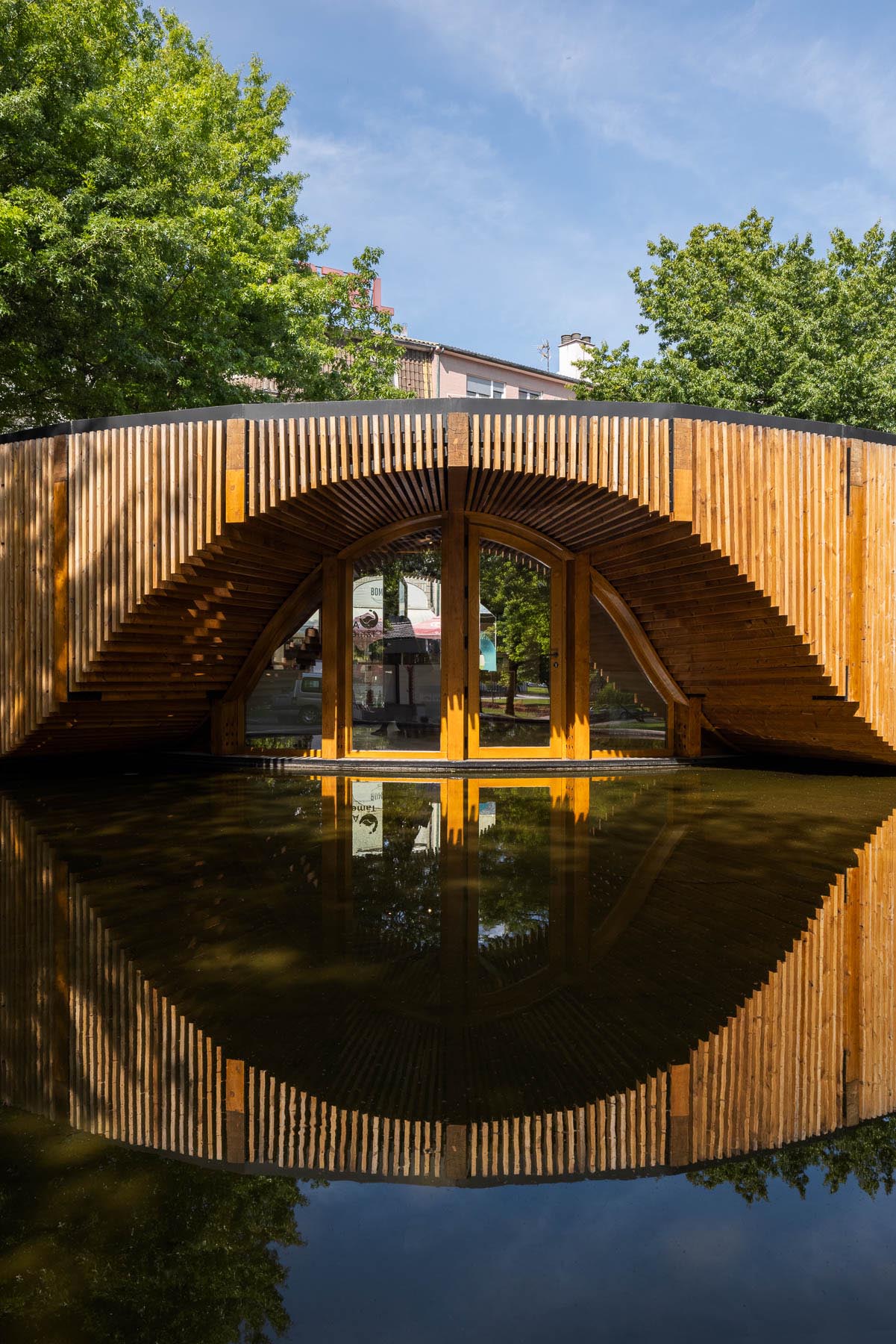 The circular design of this modern building is accented by a reflection pool and wood slat exterior.