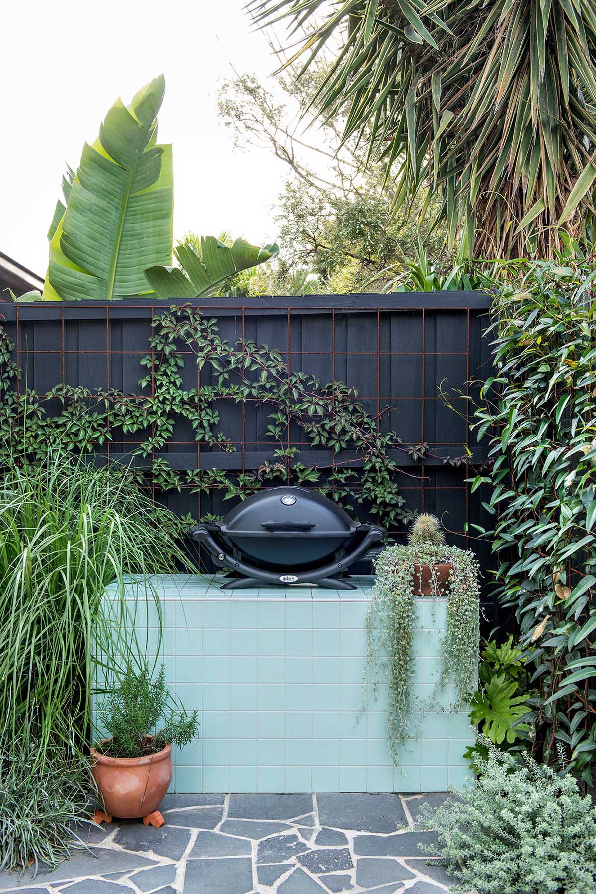 A small bbq area with a mint green tiled outdoor workspace.