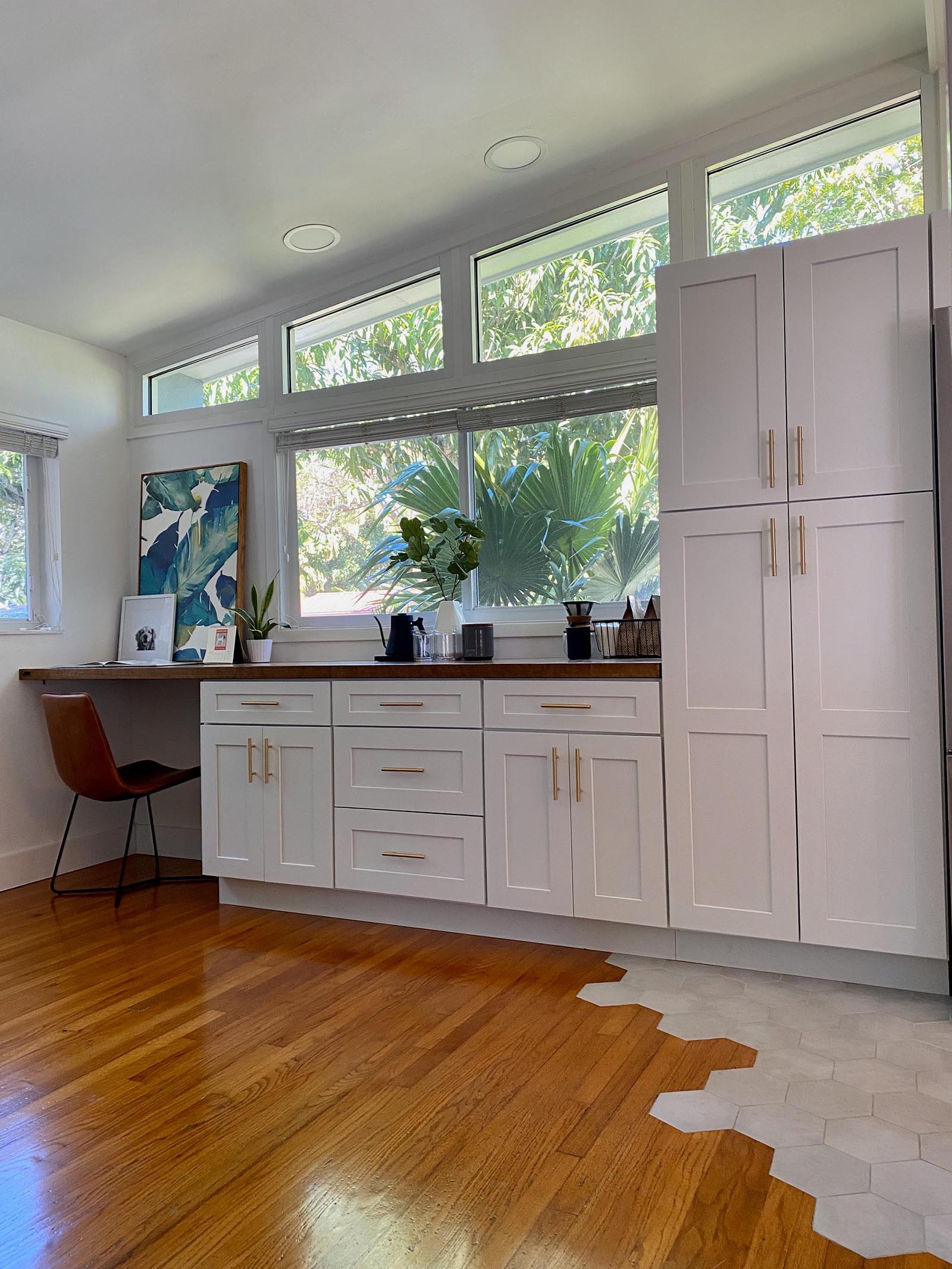 The kitchen cabinets continue along the wall and a wood countertop has been introduced to create a home office and coffee station.