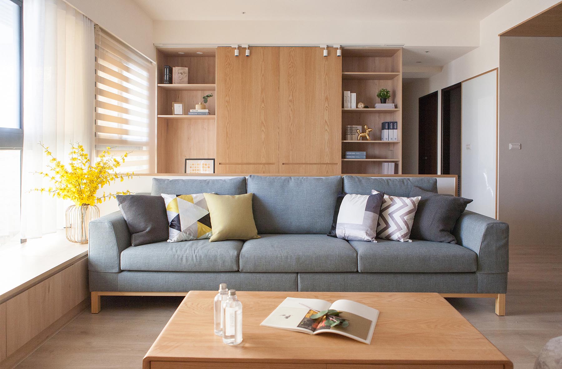 A contemporary living room with a light gray couch and wood shelving.