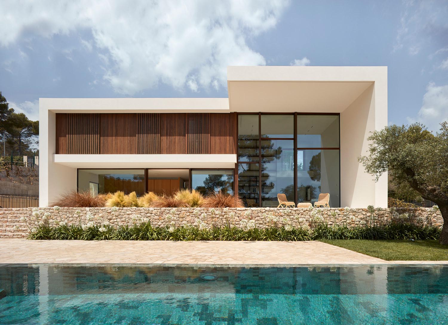 A modern house design with an off-white exterior, wood and steel accents, and a swimming pool.