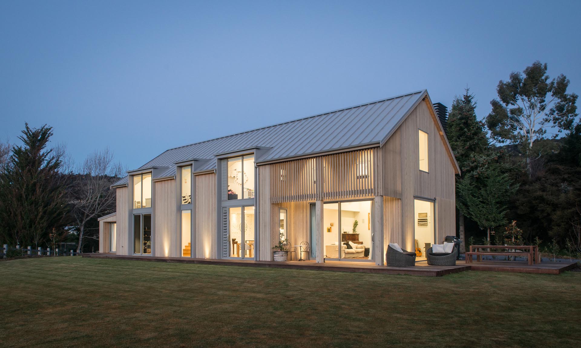 A contemporary barn-inspired home that has an exterior of pale timber tones, a sloped metal roof, and a shiplap ceiling.