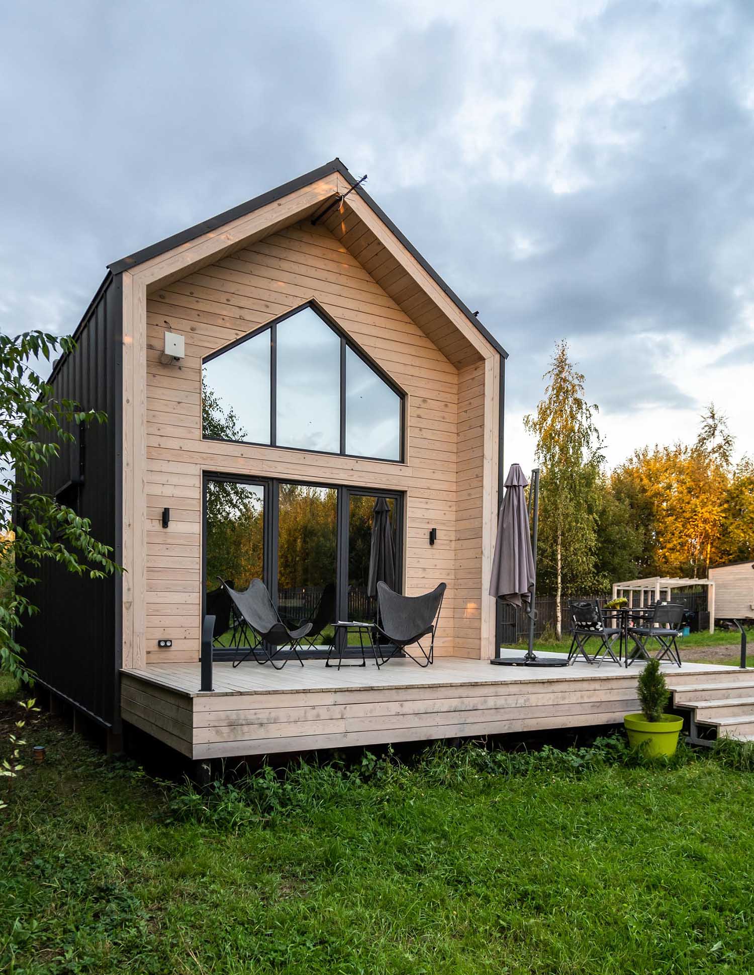 A modern barn-inspired home with a black metal exterior that's accented at each end with tongue and groove wood siding.