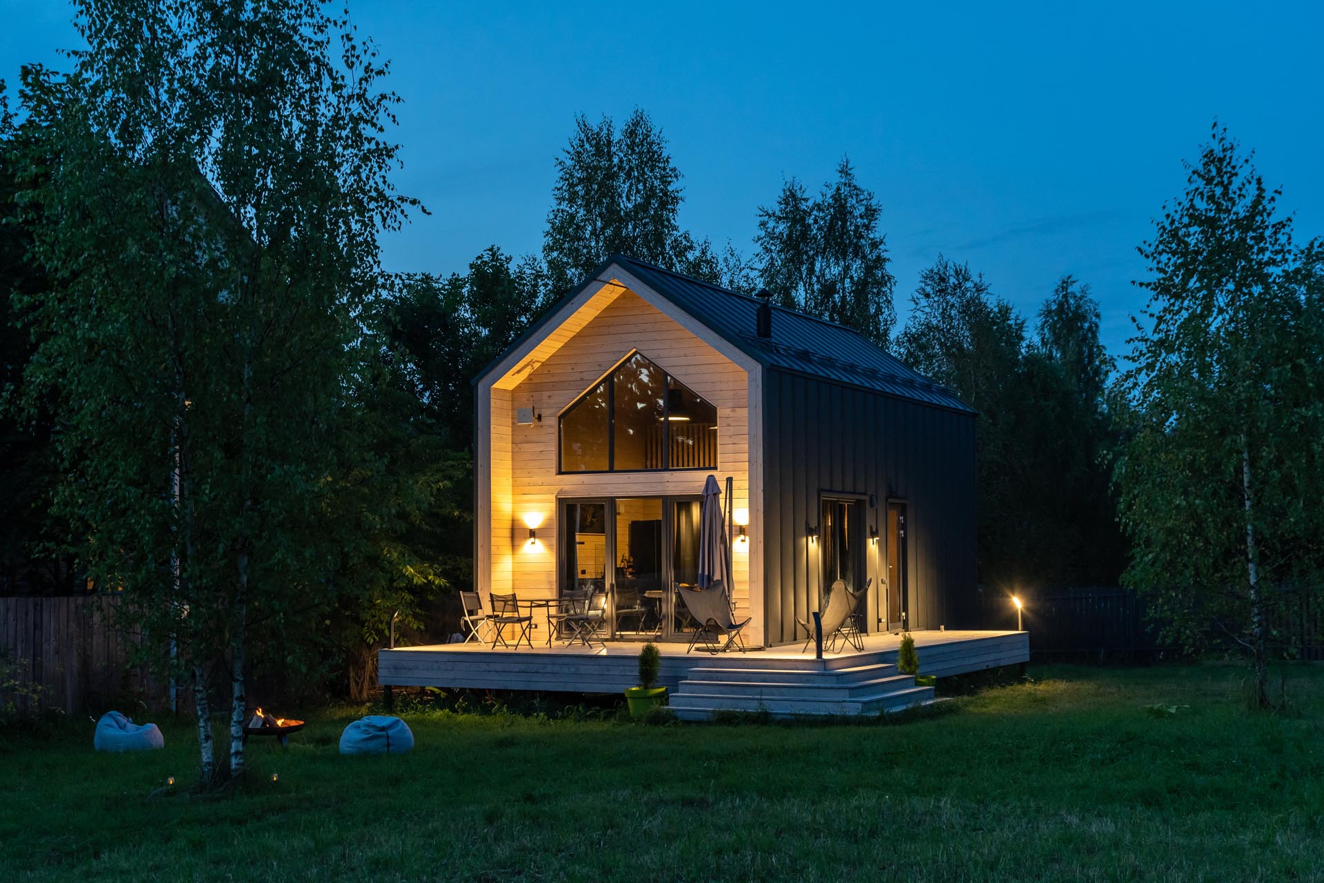 A modern barn-inspired home with a black metal exterior that's accented at each end with tongue and groove wood siding.