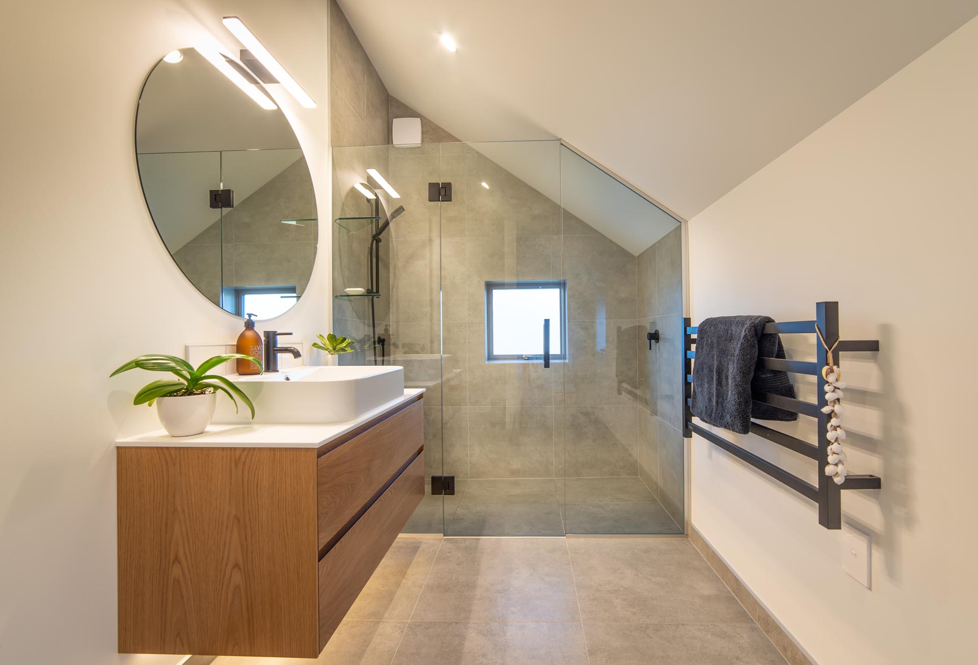 In this modern bathroom, the shower tile follows the line of the angled ceiling, while the wood vanity has hidden lighting underneath.