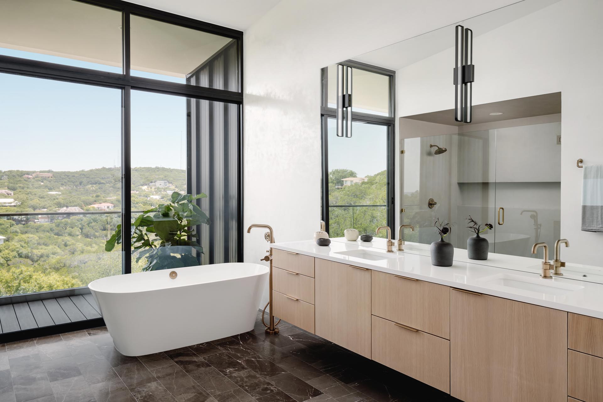 A modern bathroom with a balcony, freestanding bathtub, glass enclosed shower, and floating wood vanity.