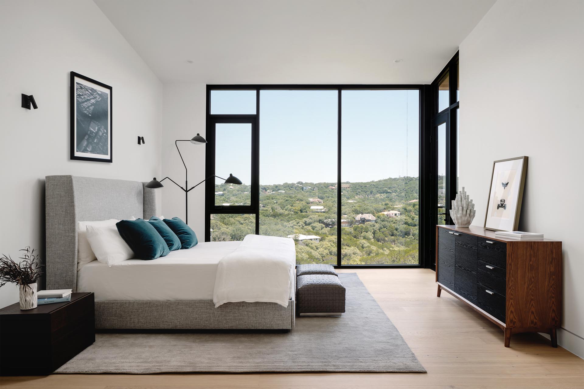 A modern bedroom with floor-to-ceiling windows that allow the tree view to be enjoyed from the bed.