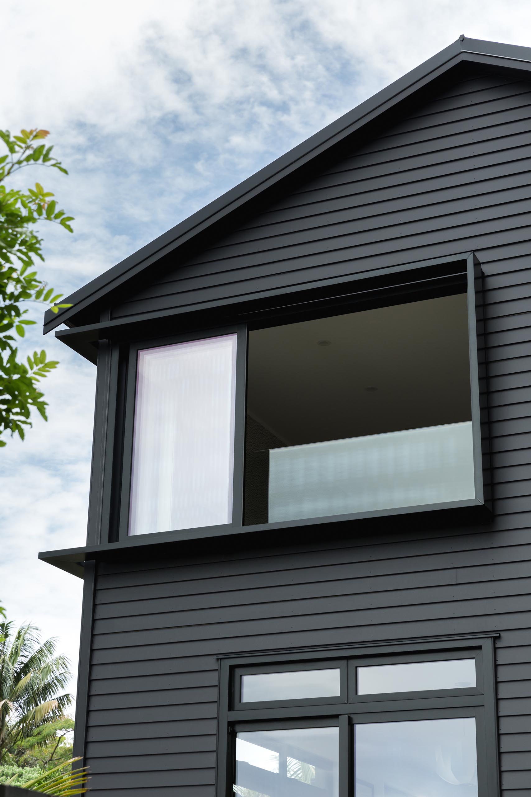 The window surround details of this modern black house are a common feature in the area, and were used to create additional light and shade detailing to the facade.