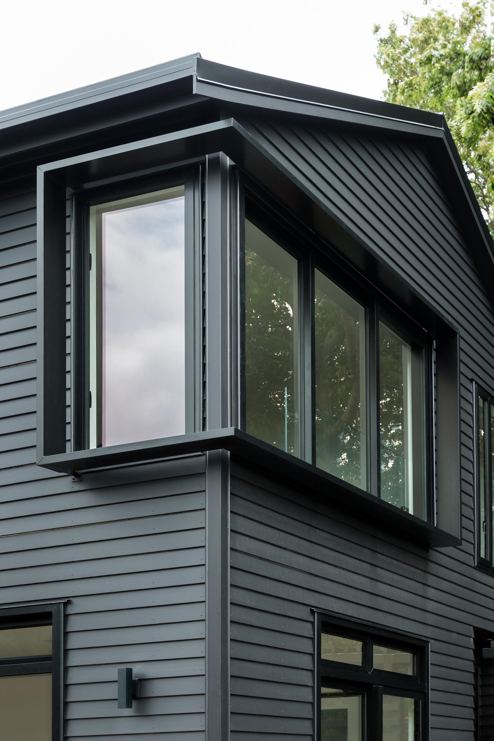 The window surround details of this modern black house are a common feature in the area, and were used to create additional light and shade detailing to the facade.