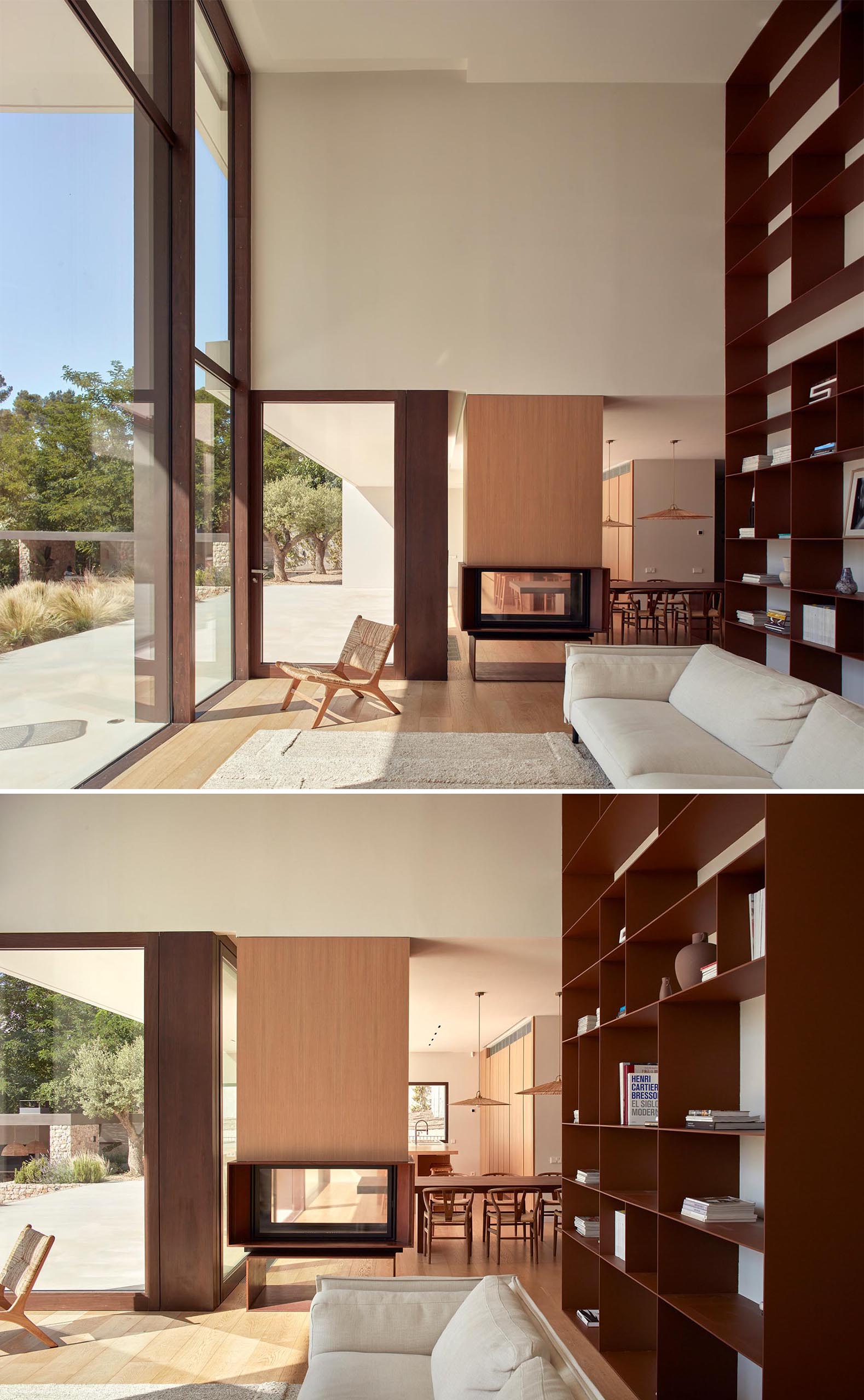 A modern living room with a double-height bookshelf and a see-through fireplace.