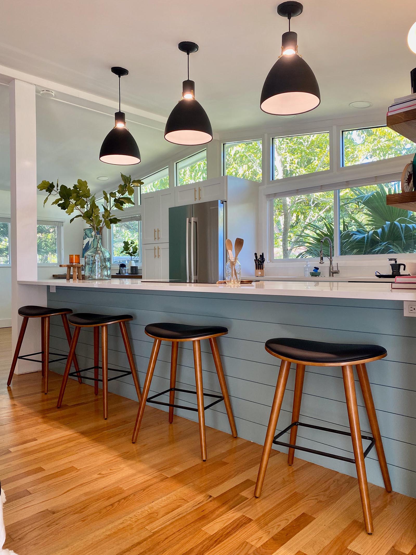 A modern and open kitchen with a peninsula, white cabinets, open wood shelving, and hexagonal floor tiles.