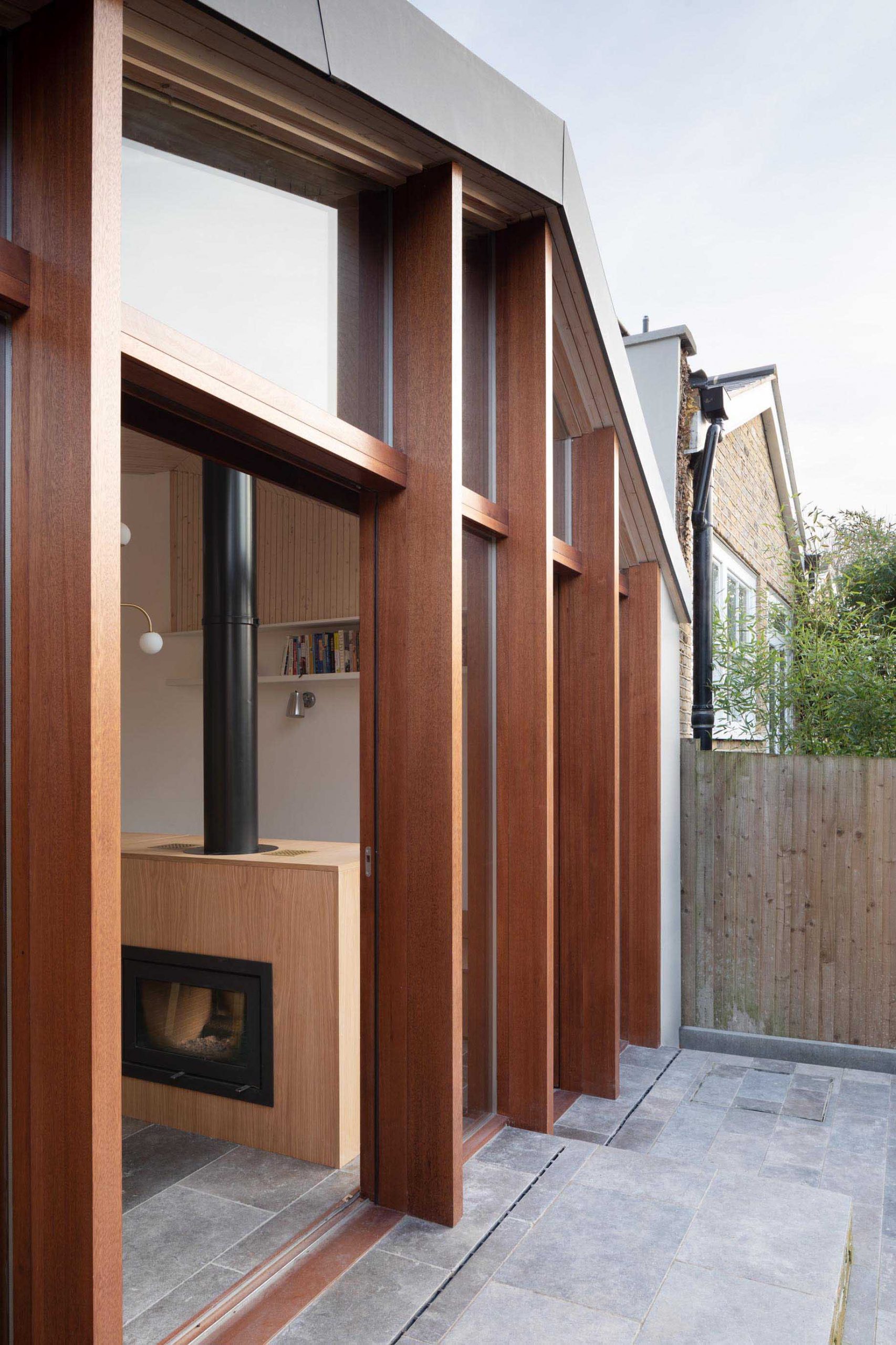 This new home addition has a wall of wood-framed windows, while the form of the roof allows light to get to the back of the interior.