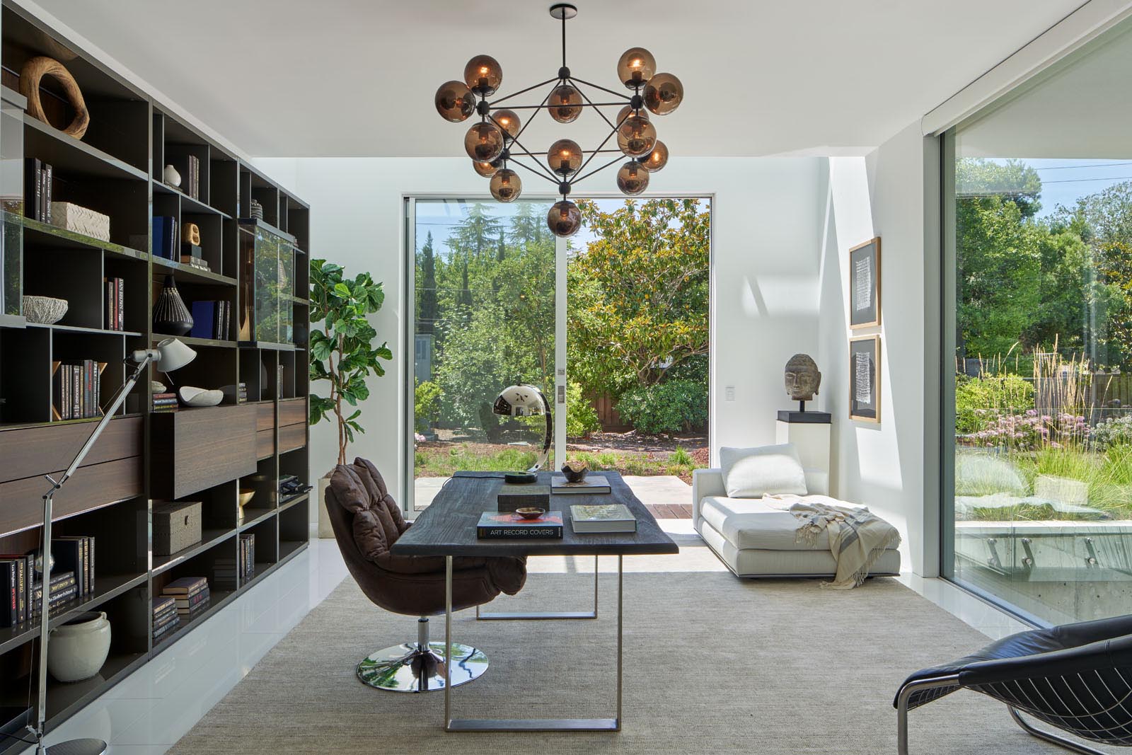 In a home office, a dark bookshelf provides a backdrop for the desk, while a sculptural light fixture adds interest to the room.