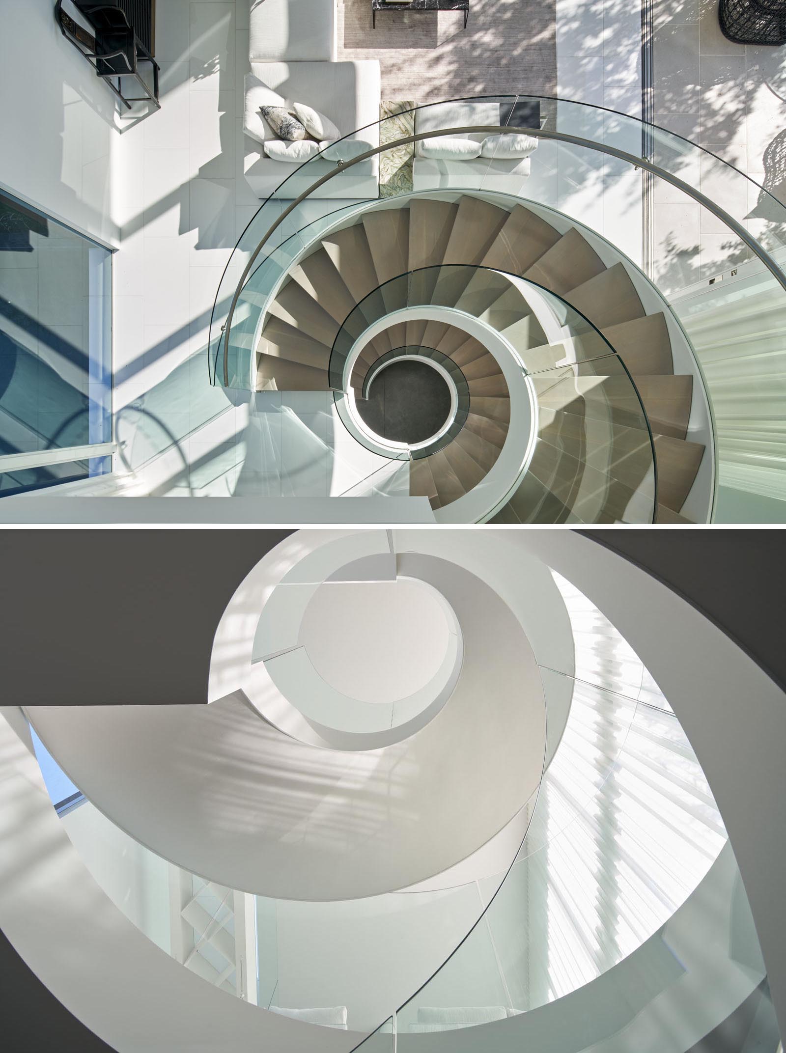 This custom designed spiral staircase includes glass handrails and a steel frame that complements the surrounding white walls.