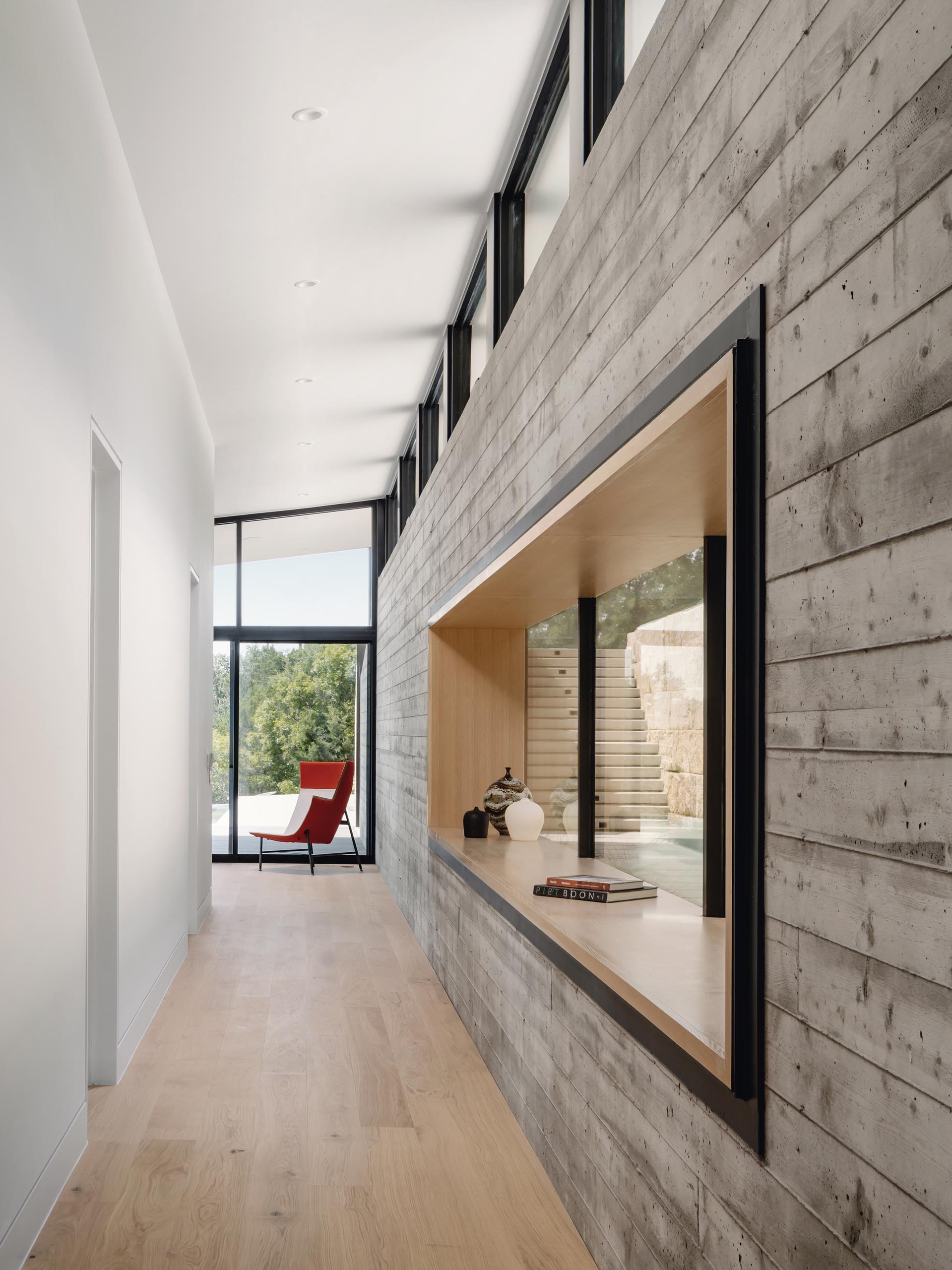 A hallway connecting the two living rooms provides a close-up look at the board-formed concrete wall, and access to the bedrooms and bathrooms.