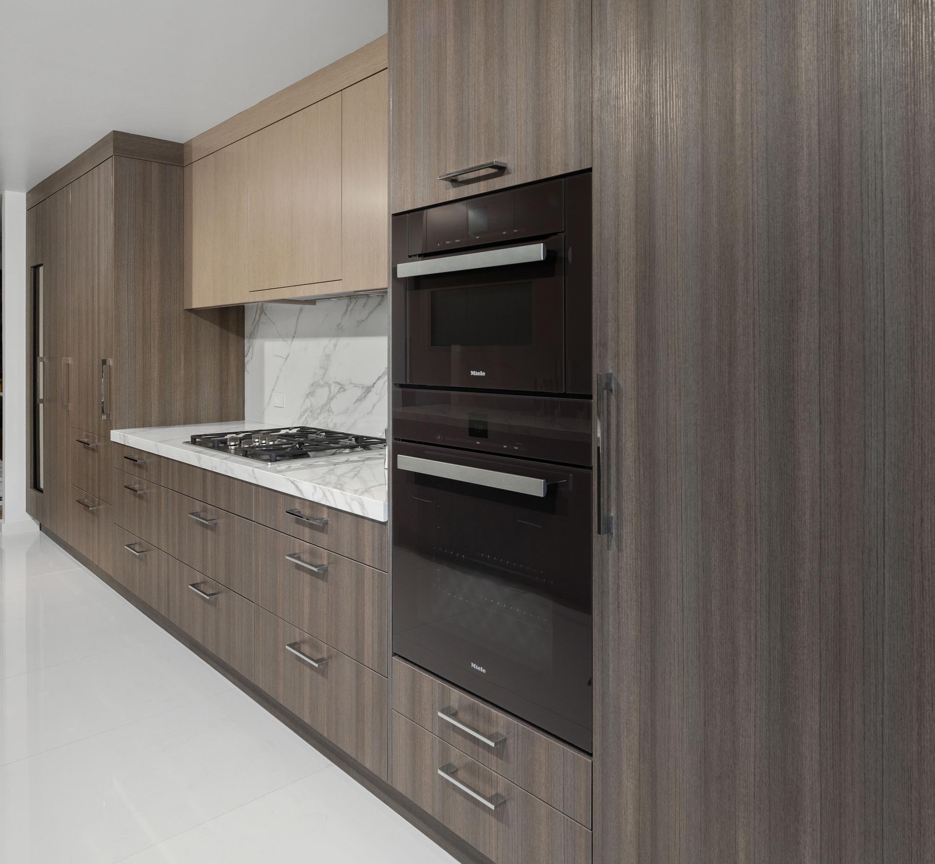 This updated kitchen includes a wall of floor-to-ceiling cabinetry that integrates the fridge and a wine refrigerator.