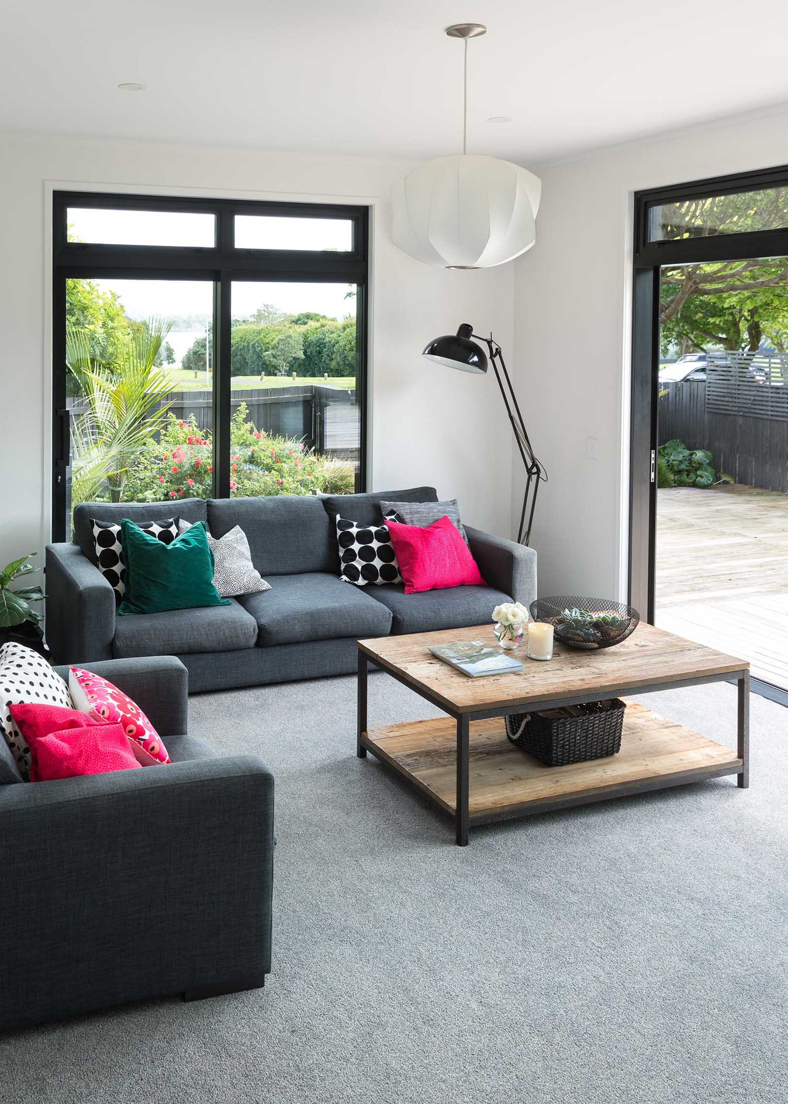 This modern living room includes white walls, grey carpet, and bold black window frames.