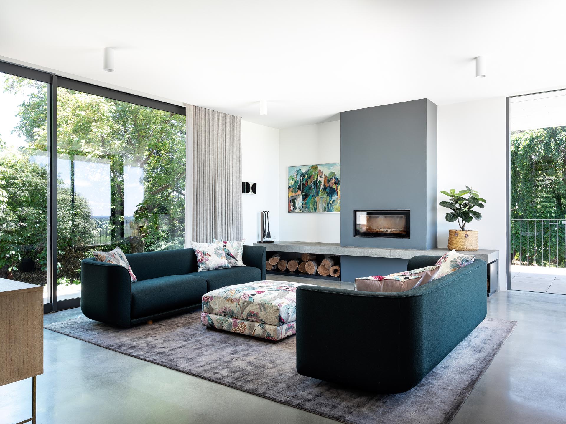 This modern living room palette includes rich greens, textured marble, timber, and touches of florals and pinks in the upholstery, soft furnishings, and art.