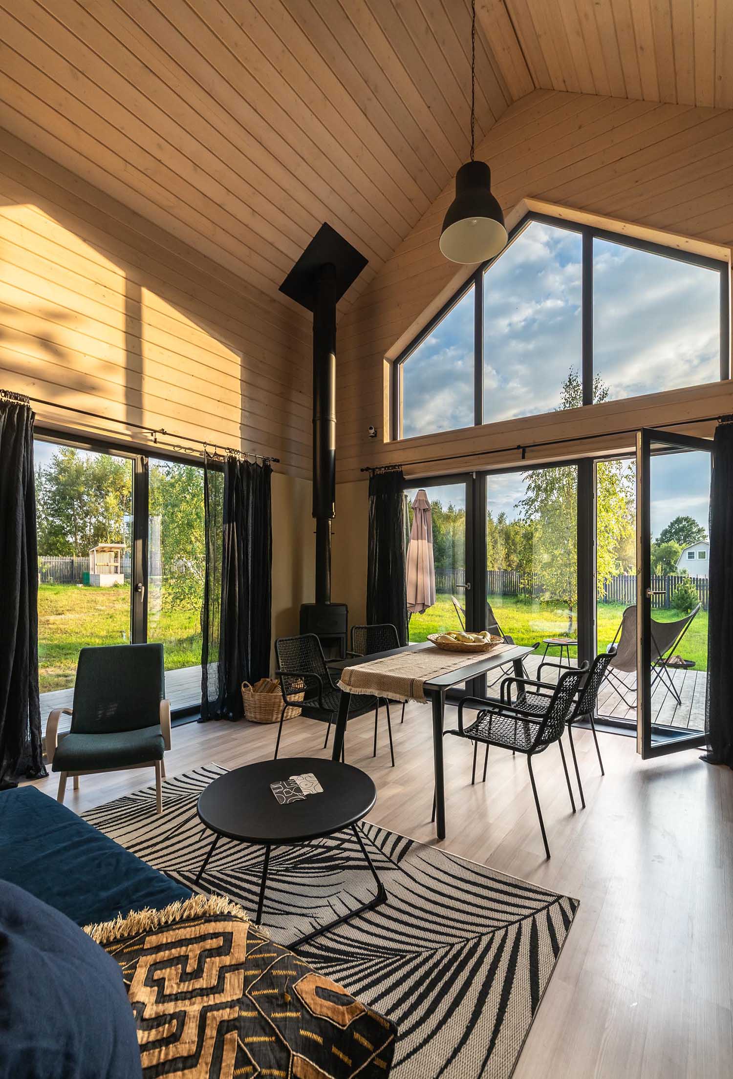 A modern barn-inspired living room with tongue and groove wood siding and black accents, like a fireplace, the curtains, and furniture.