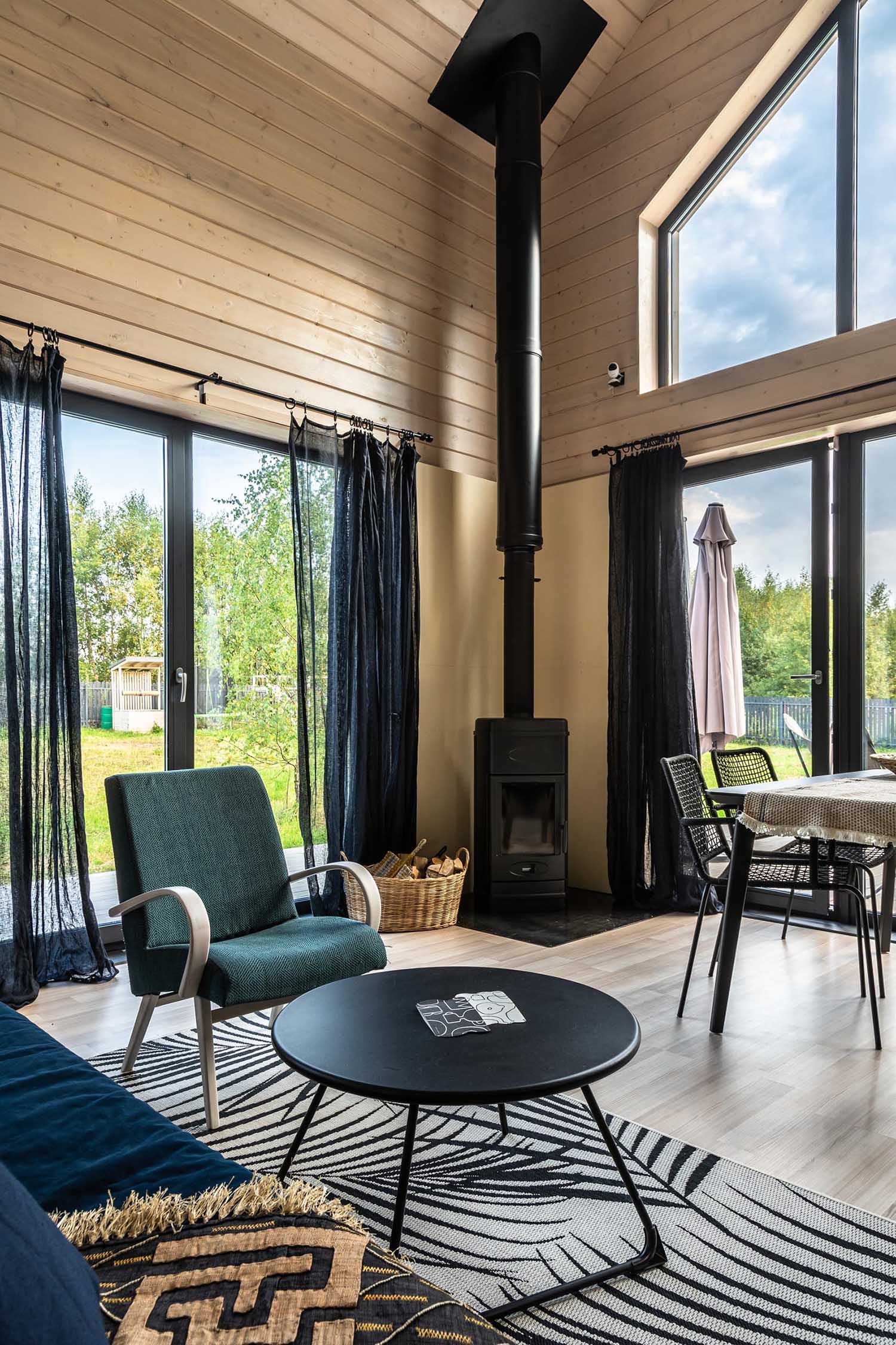 A modern barn-inspired living room with tongue and groove wood siding and black accents, like a fireplace, the curtains, and furniture.