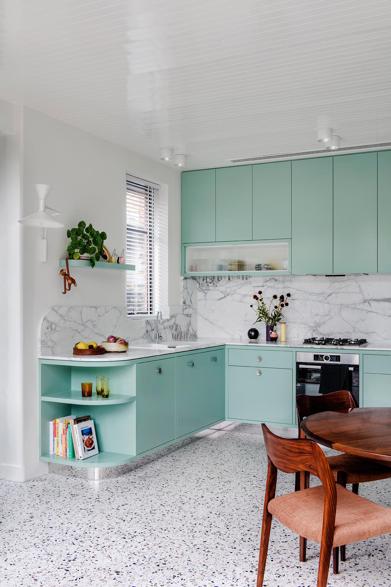 A modern mint green kitchen with Calacatta Statuario countertops, Terrazzo flooring, and white walls and ceiling.
