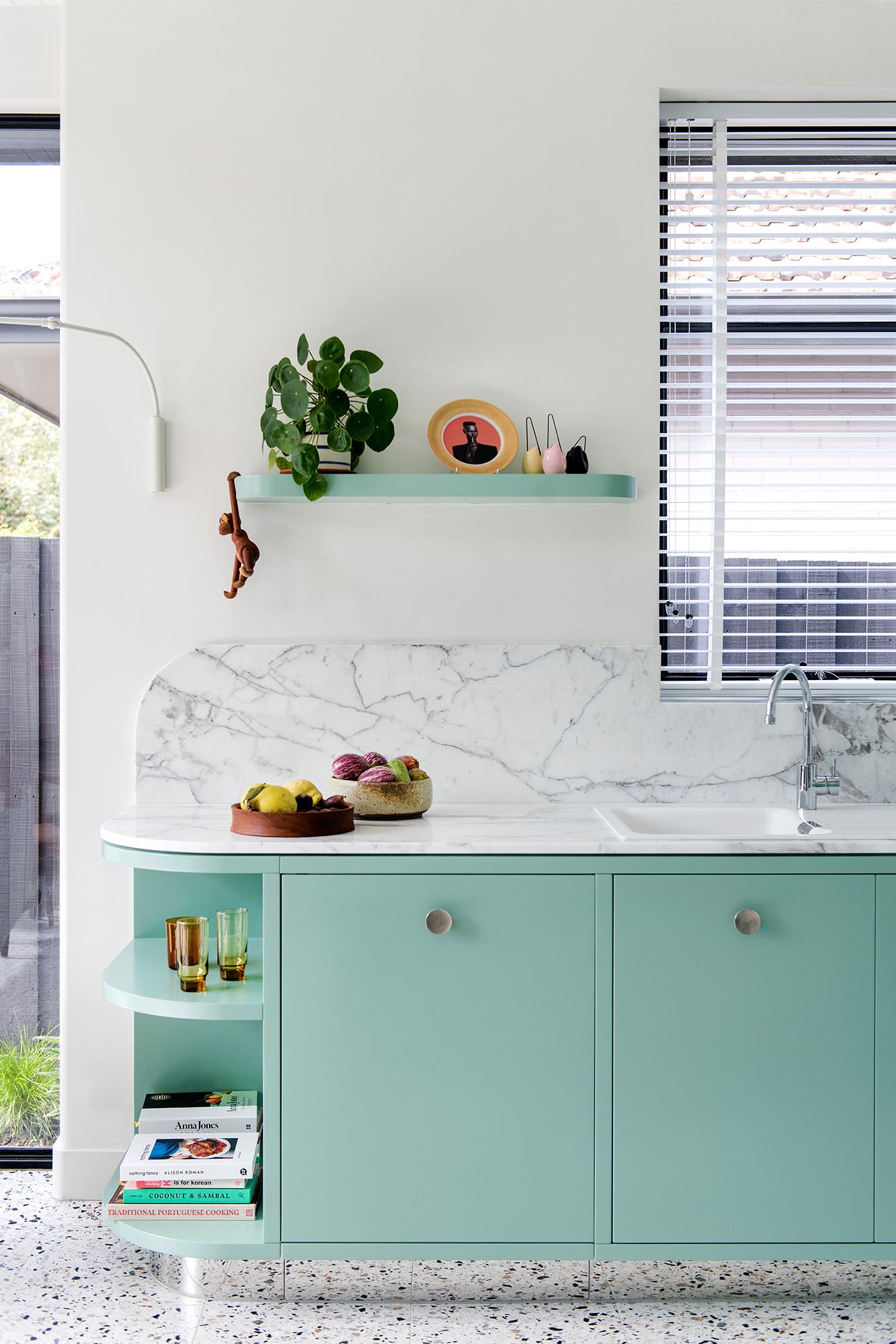 A modern mint green kitchen with Calacatta Statuario countertops, Terrazzo flooring, and white walls and ceiling.