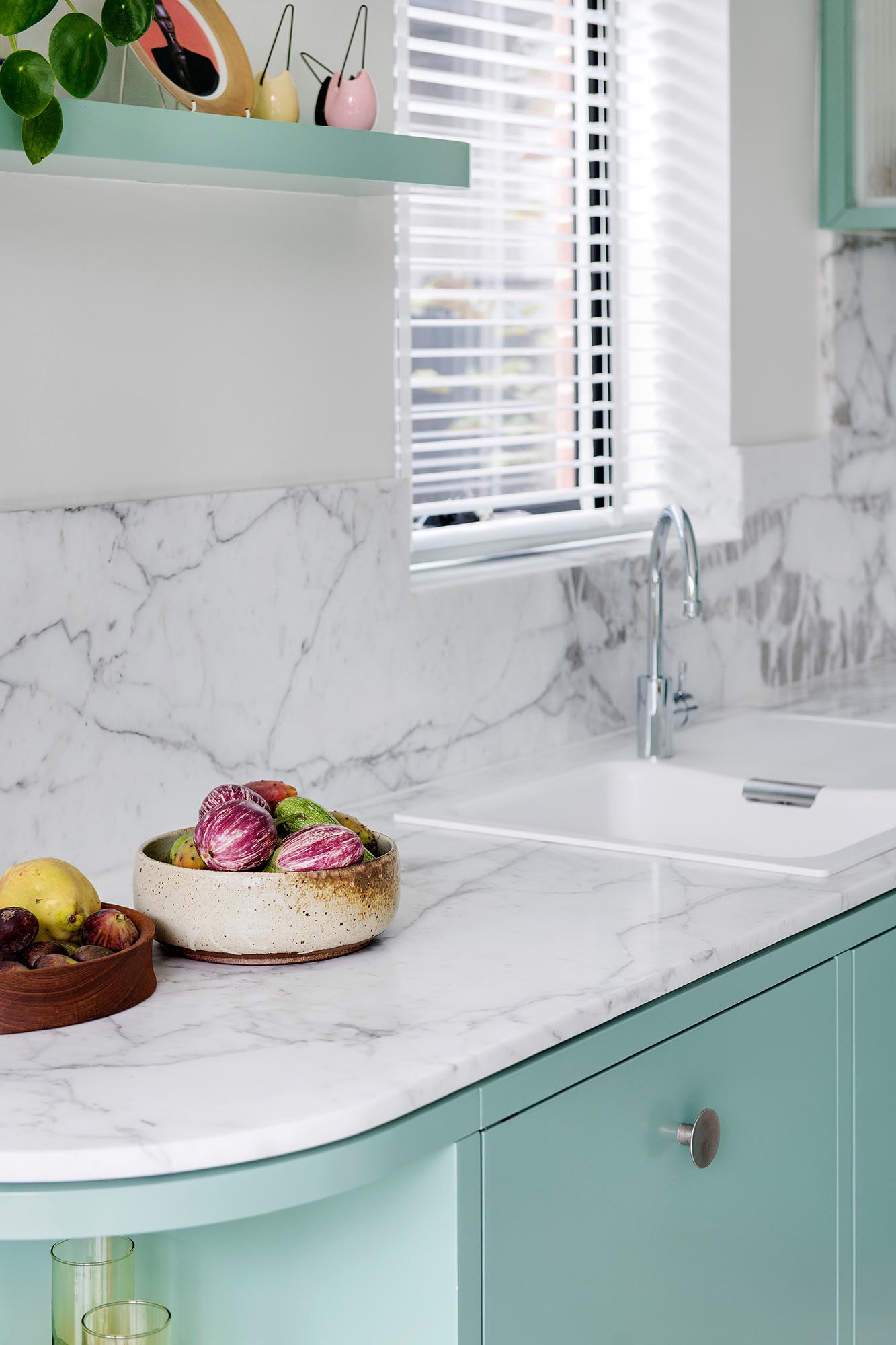 A modern mint green kitchen with Calacatta Statuario countertops, Terrazzo flooring, and white walls and ceiling.