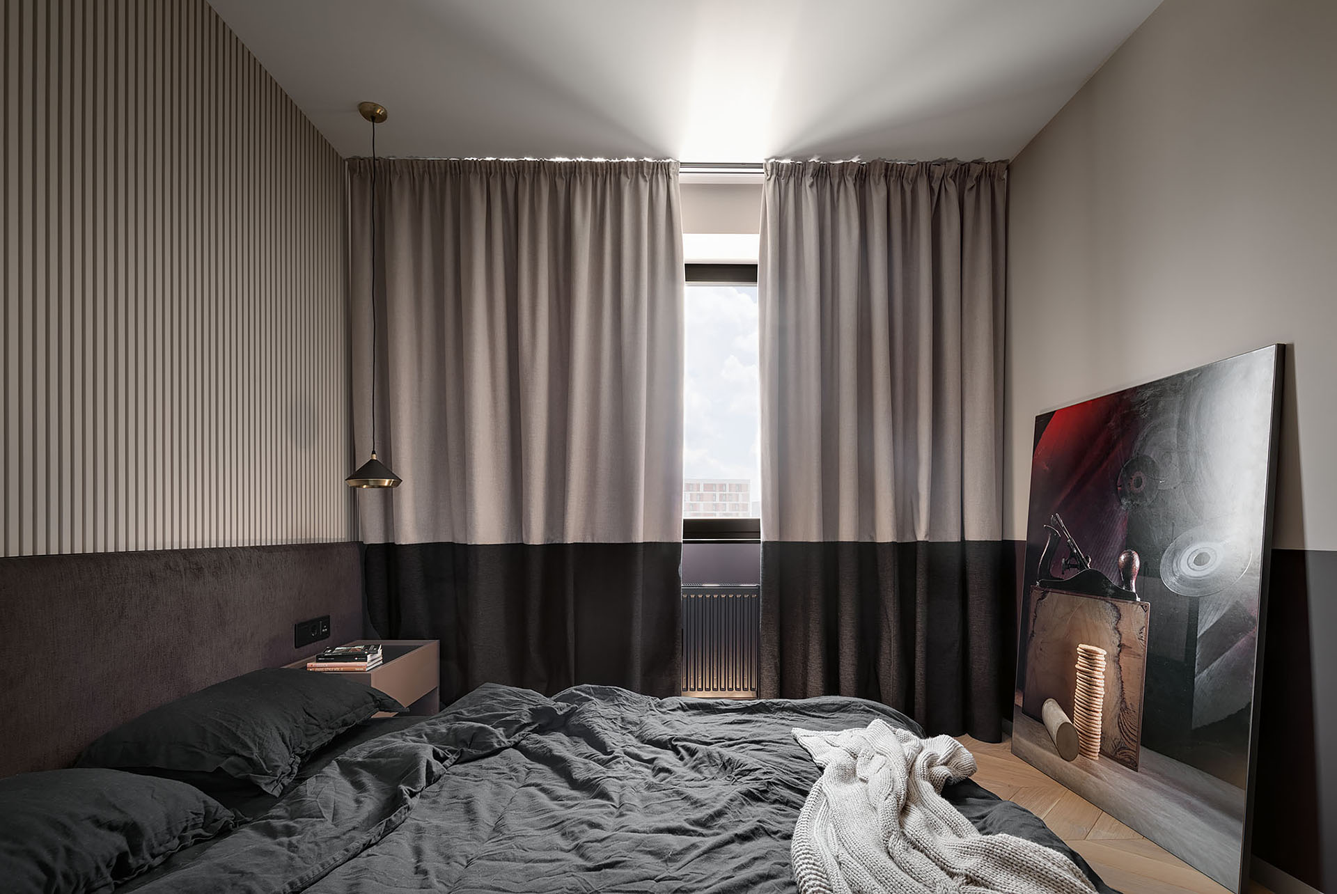 A two-tone bedroom includes different shades of chocolate and beige, a textured accent wall made from plaster, and two-tone curtains.