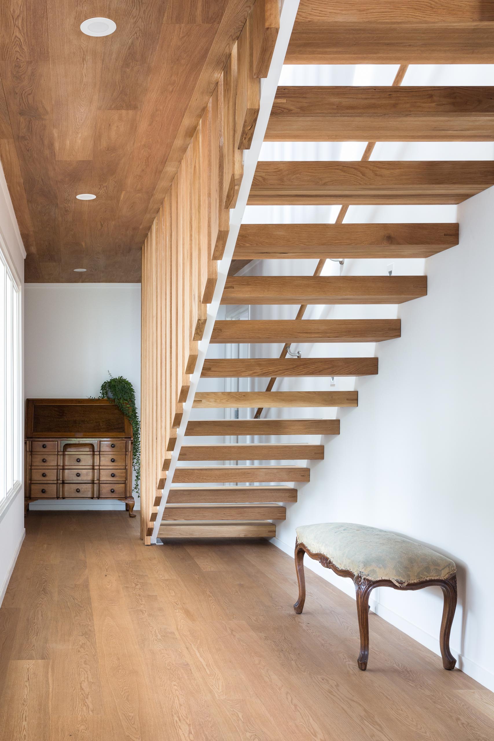 A steel and floating oak staircase with robust timber balusters and embedded stainless steel strips within the stair treads that create a non slip surface.