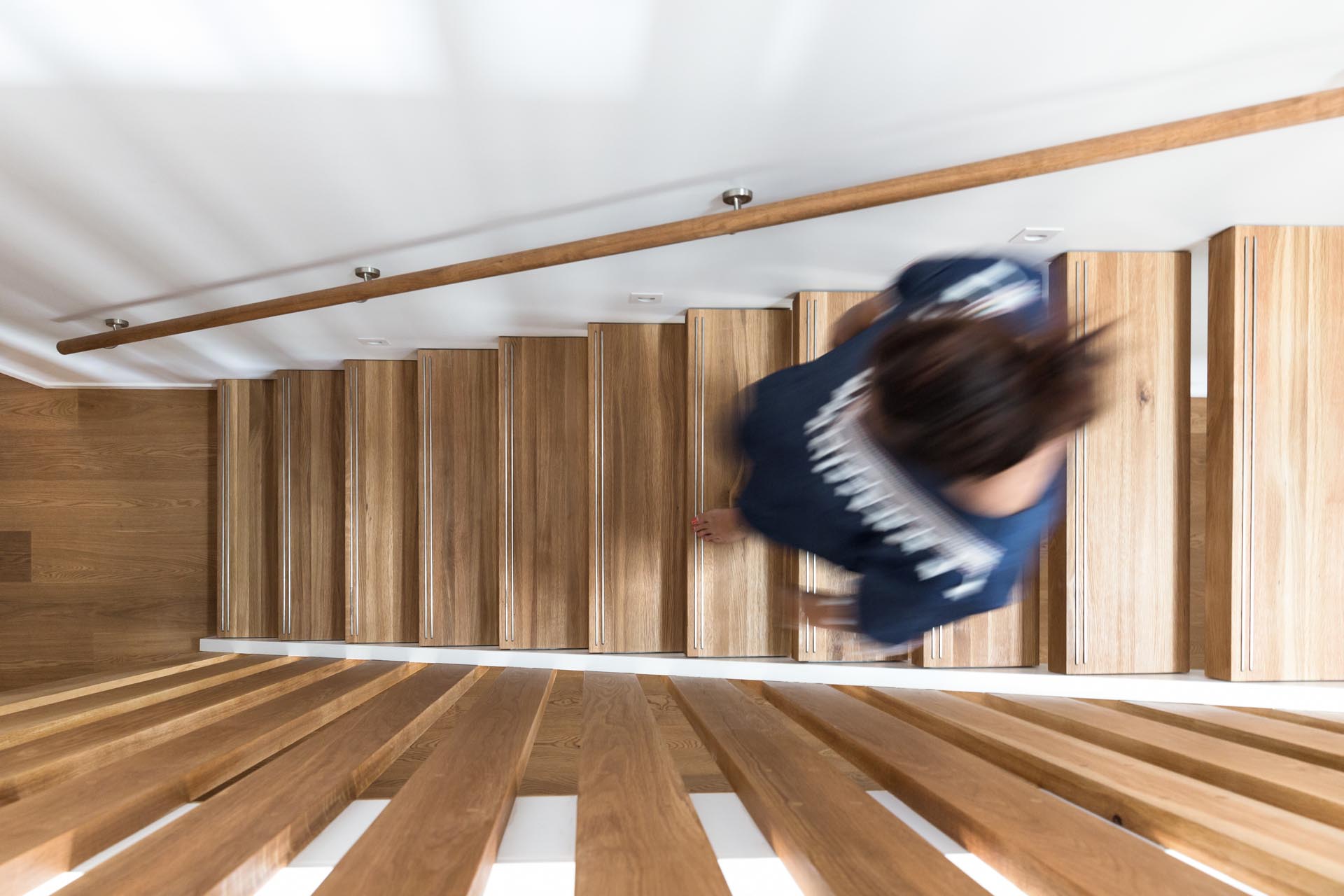 A steel and floating oak staircase with robust timber balusters and embedded stainless steel strips within the stair treads that create a non slip surface.