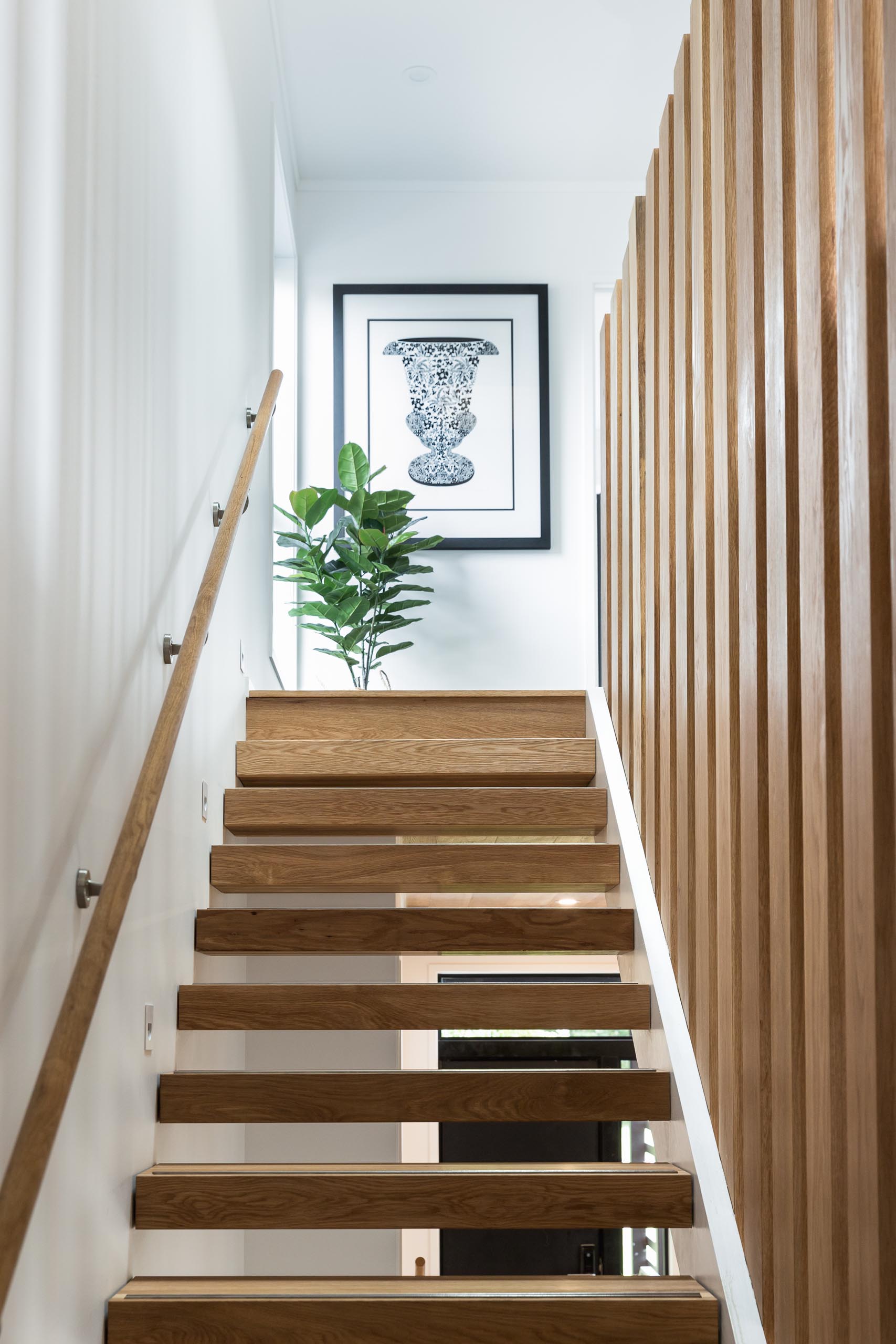 A steel and floating oak staircase with robust timber balusters and embedded stainless steel strips within the stair treads that create a non slip surface.