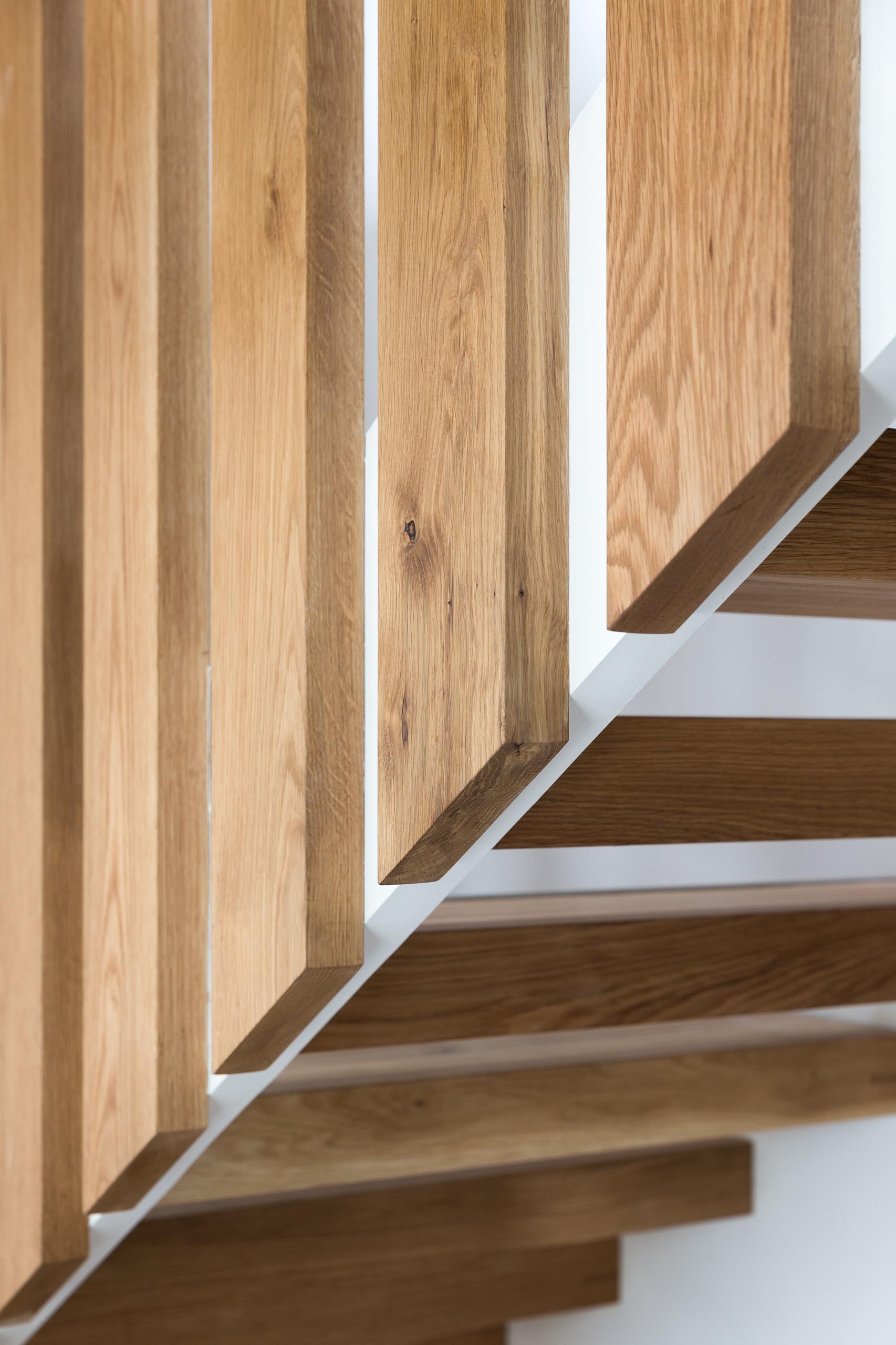 A steel and floating oak staircase with robust timber balusters and embedded stainless steel strips within the stair treads that create a non slip surface.