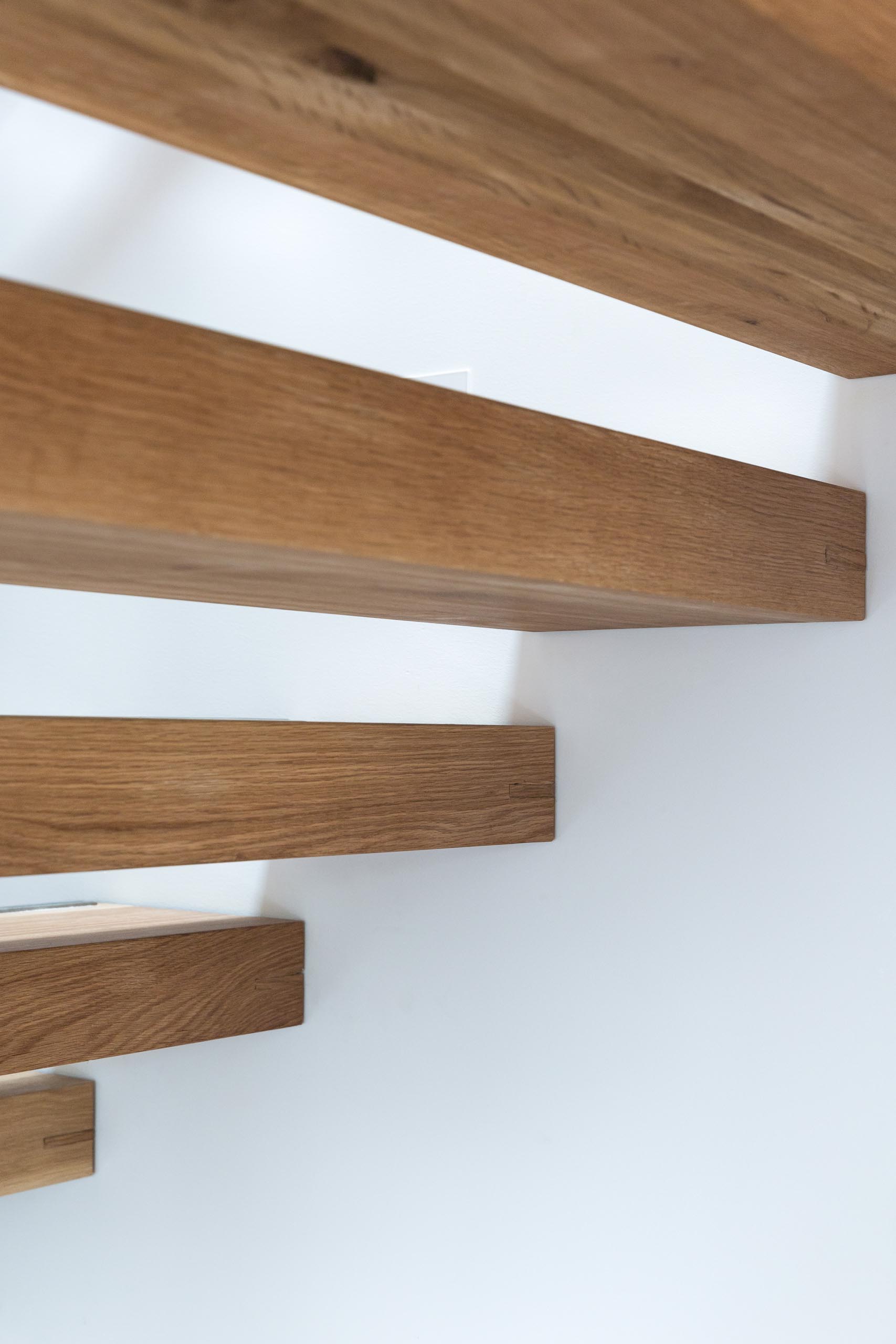 A steel and floating oak staircase with robust timber balusters and embedded stainless steel strips within the stair treads that create a non slip surface.