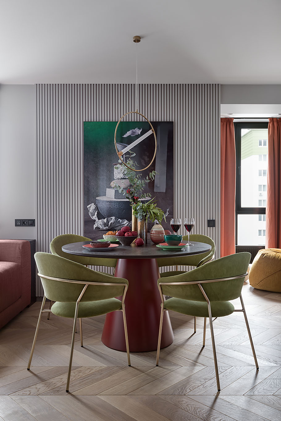 Separating the living space from the kitchen is a round dining table, a minimalist pendant light, and chairs with metallic frames.