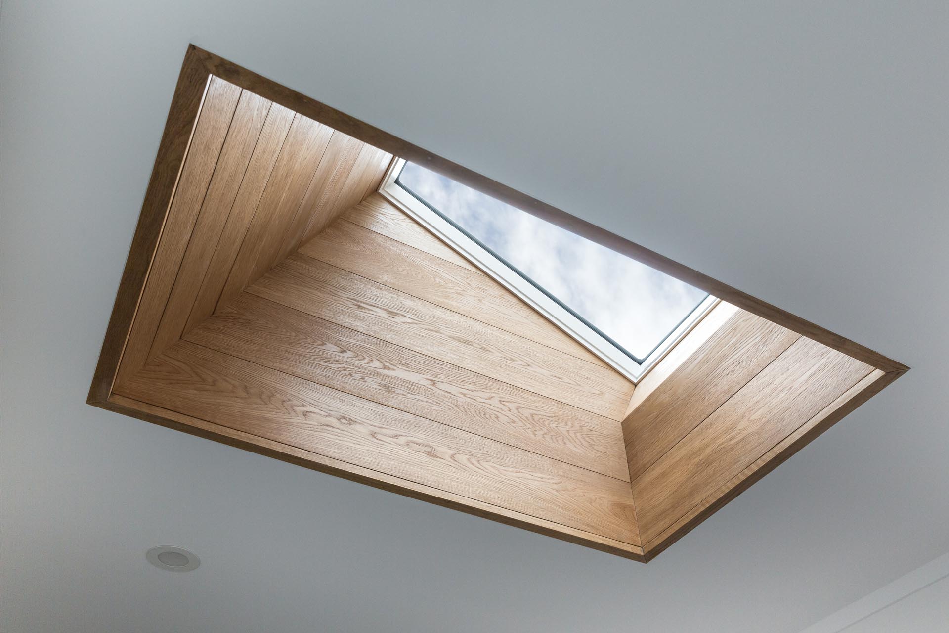 A wood lined skylight adds extra natural light to the stairwell below.