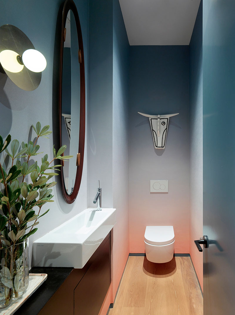 A colorful powder room that features an ombre wallpaper and an ox mask by Norwegian artist Arne Lindaas.