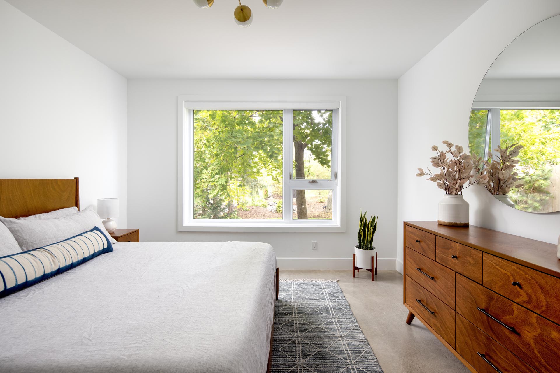 In this modern bedroom, the furnishings have been kept minimal, with wood furniture and plants adding a natural element to the room.