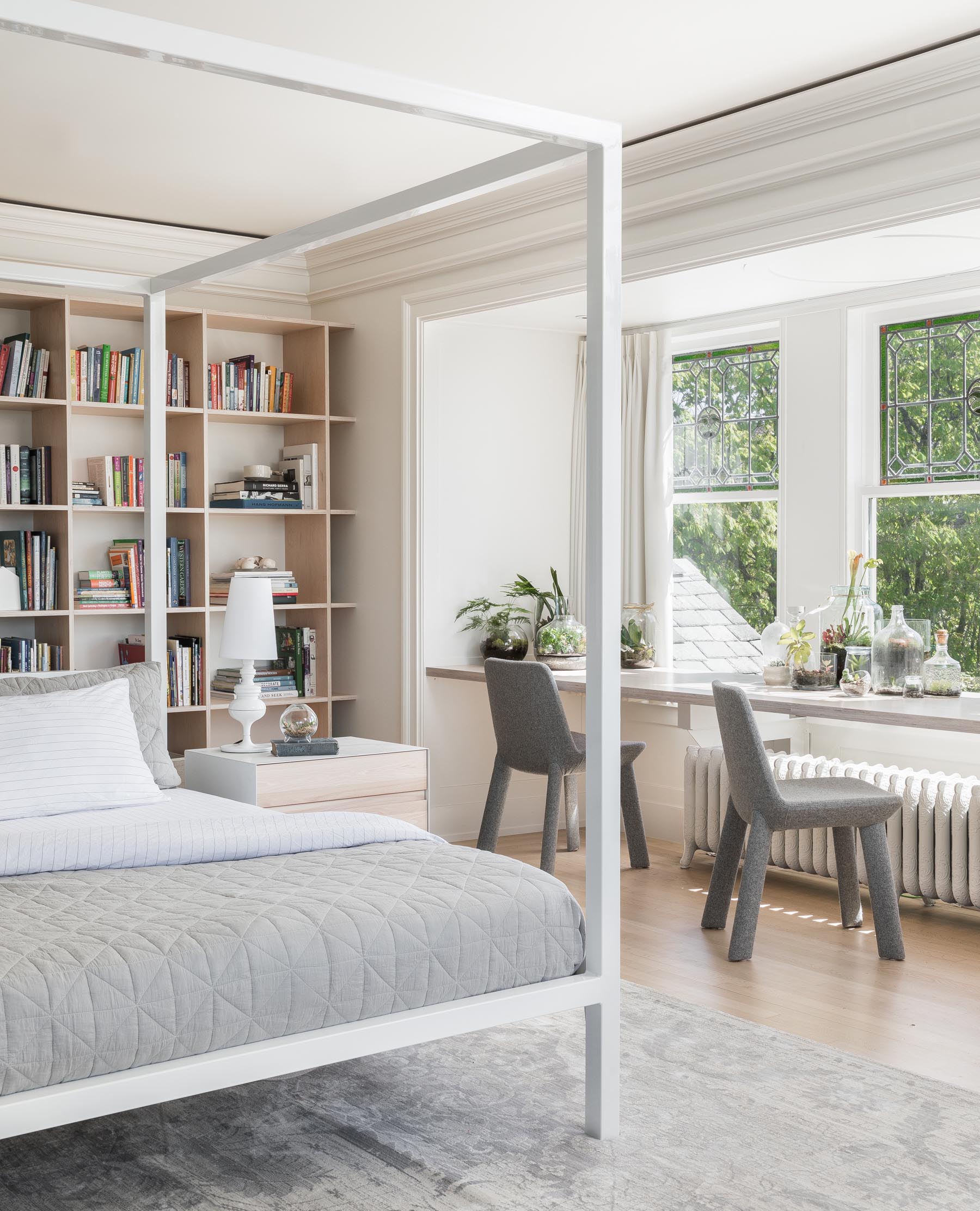 In a modern master bedroom, a wood desk spans the width of the windows, and provides a place for two to sit at.