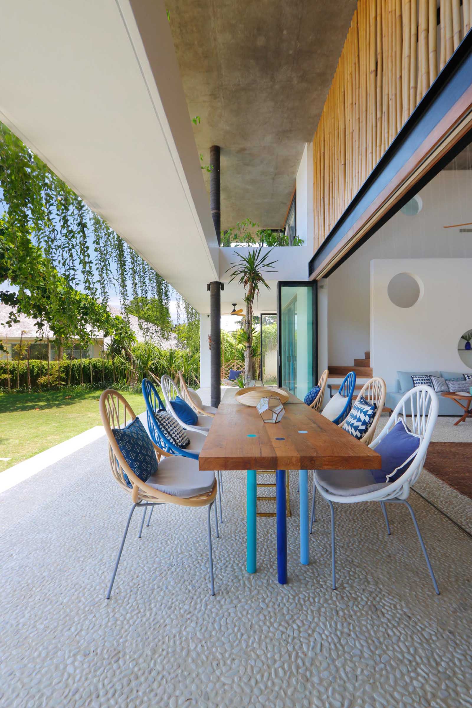A modern beach house with a covered outdoor dining area.