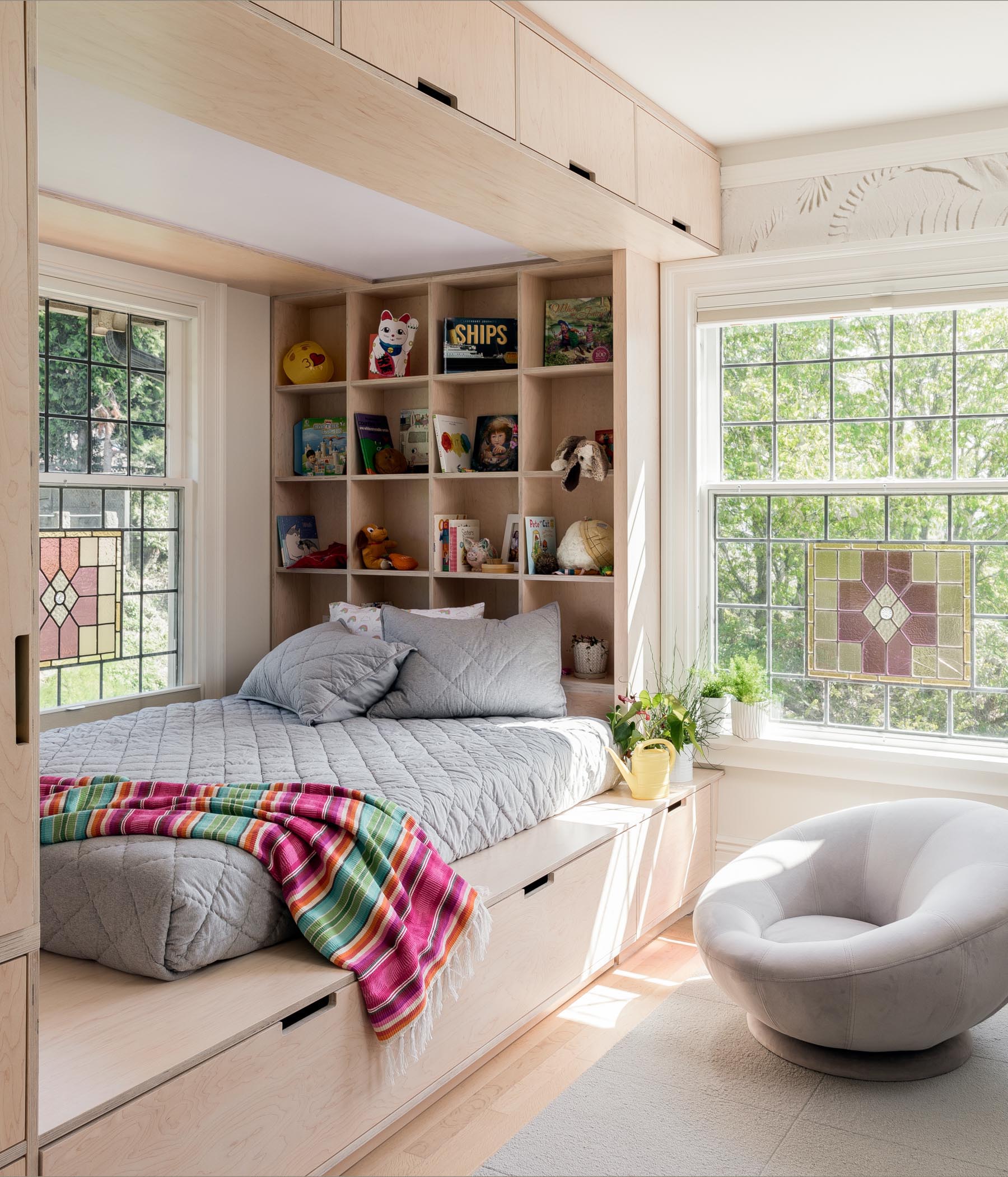 A custom wood bed design has plenty of storage including cabinets, drawers, and open shelving.